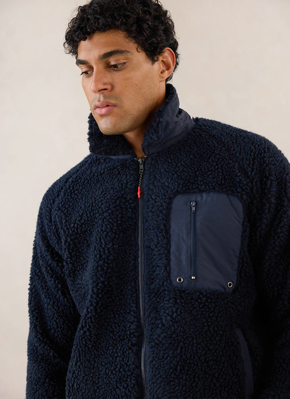 Close-up of a model wearing the navy wool fleece jacket from Percival, highlighting the zippered pocket and high collar.
