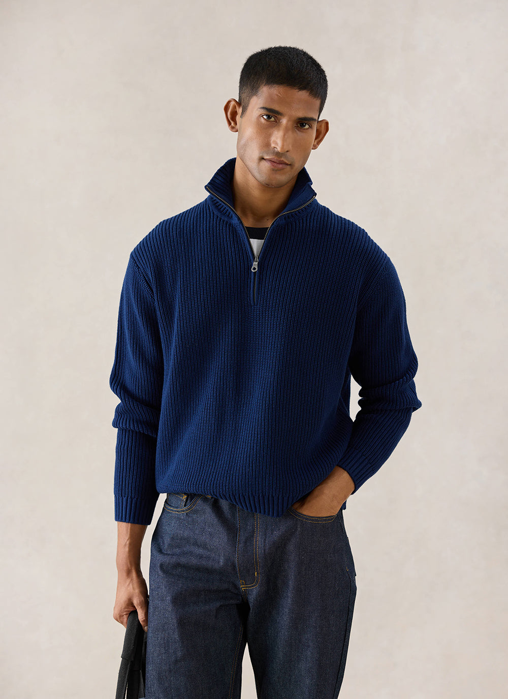 A model wears the navy Percival Meyer Boxy Quarter Zip, styled with dark denim jeans in a studio shot.