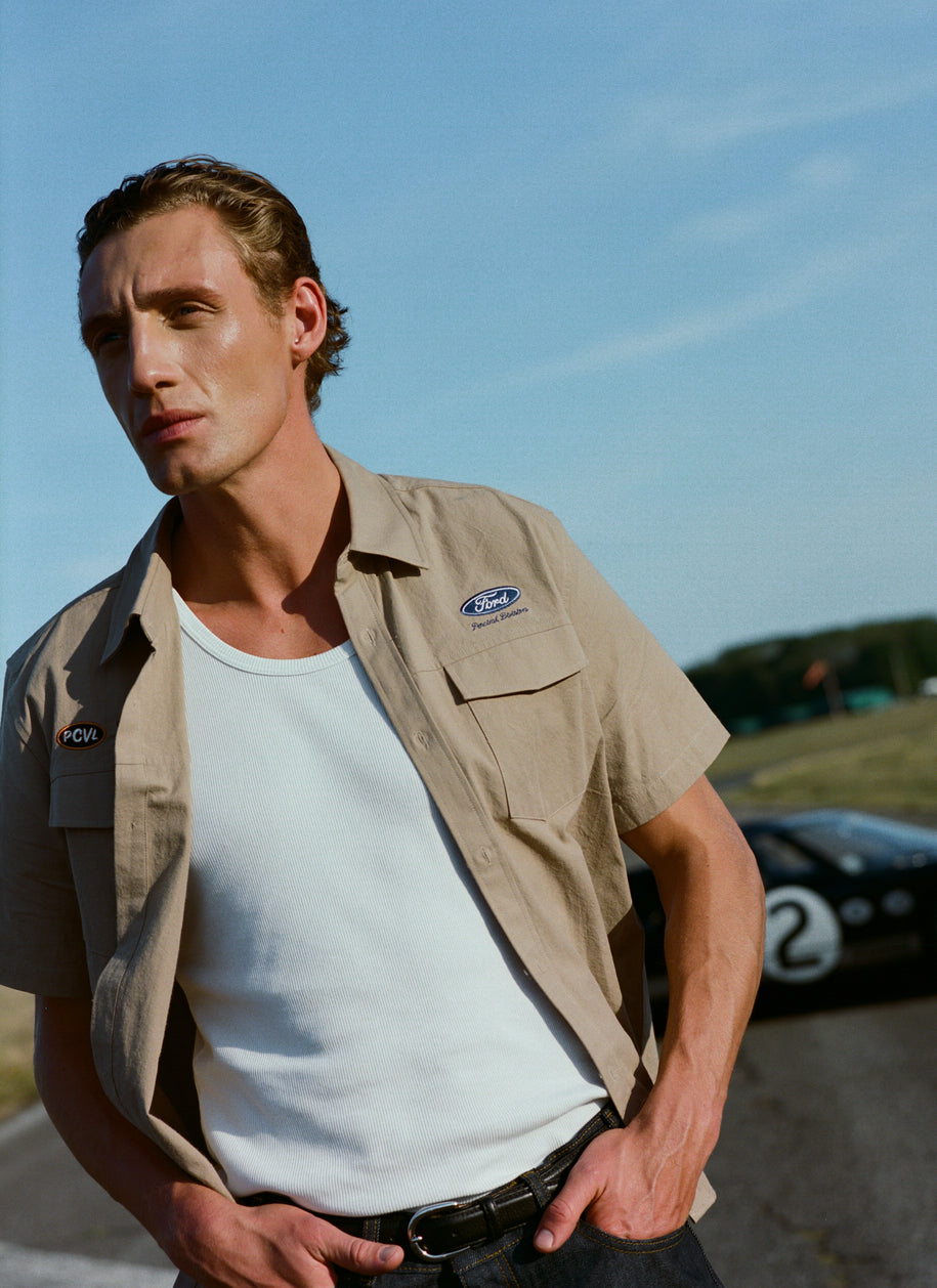 Tan Ford x Percival work shirt over a white vest, styled with dark indigo heritage denim jeans outdoors.