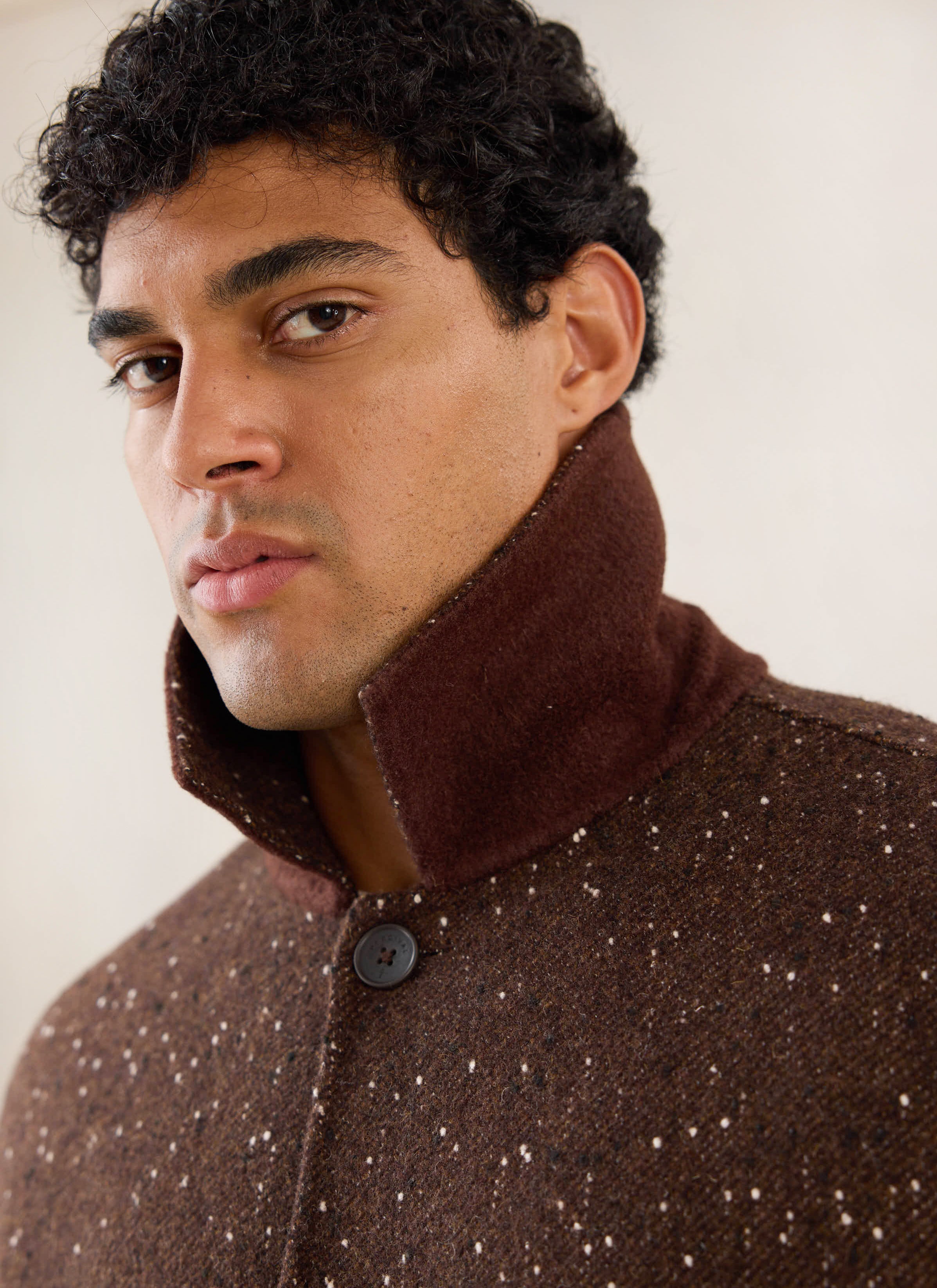 Close-up portrait of a model wearing the brown fleck Minnesota Overcoat from Percival with a popped collar.