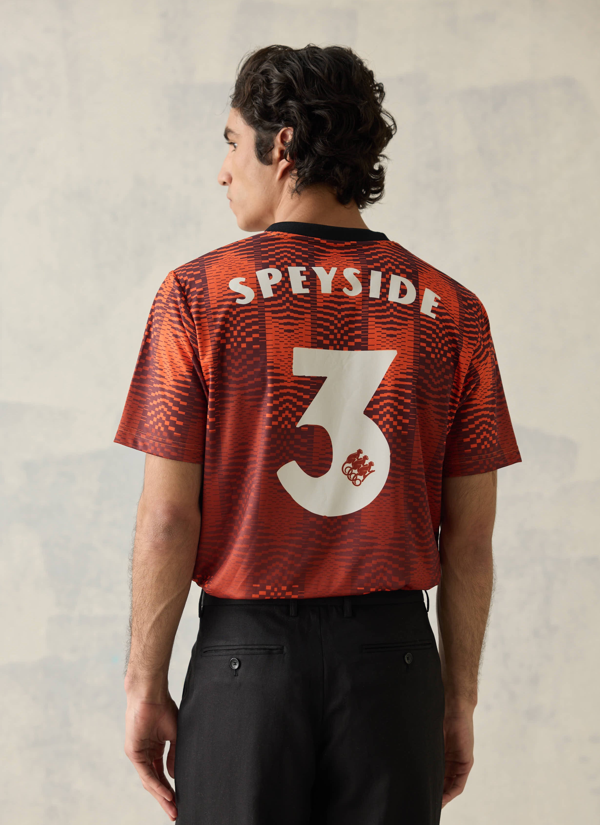 Orange pixel-stripe Percival x Monkey Shoulder football shirt shown from behind with white Speyside text and a number 3.