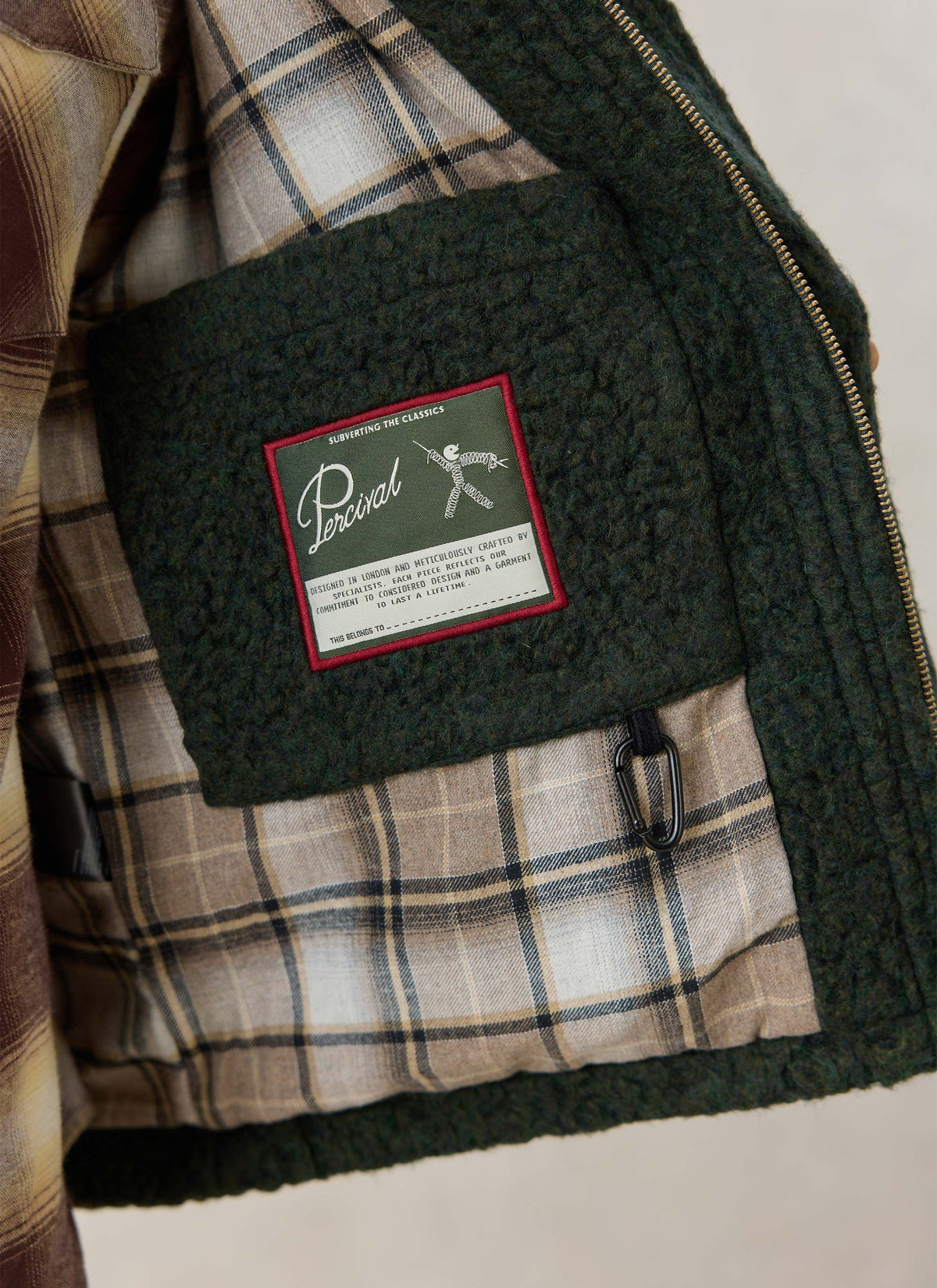 Inside of the Percival Murrey fleece jacket in forest green, showcasing the checked lining and branded label.