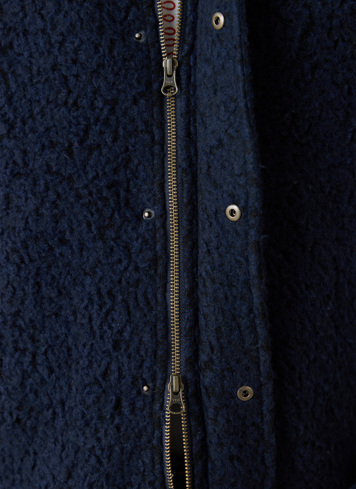 A close-up of the Percival navy wool-blend fleece jacket showing the two-way zipper and press-stud placket details.