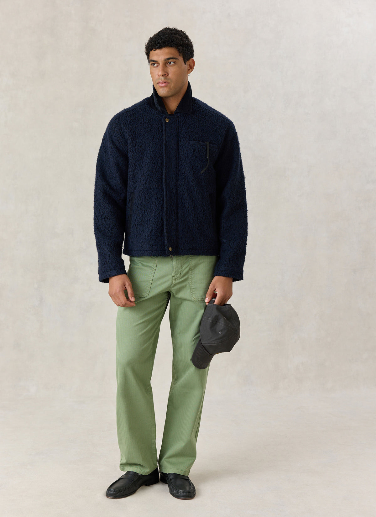 A model wearing the navy blue Percival wool-blend Murrey fleece jacket with a contrast cord collar and green trousers.