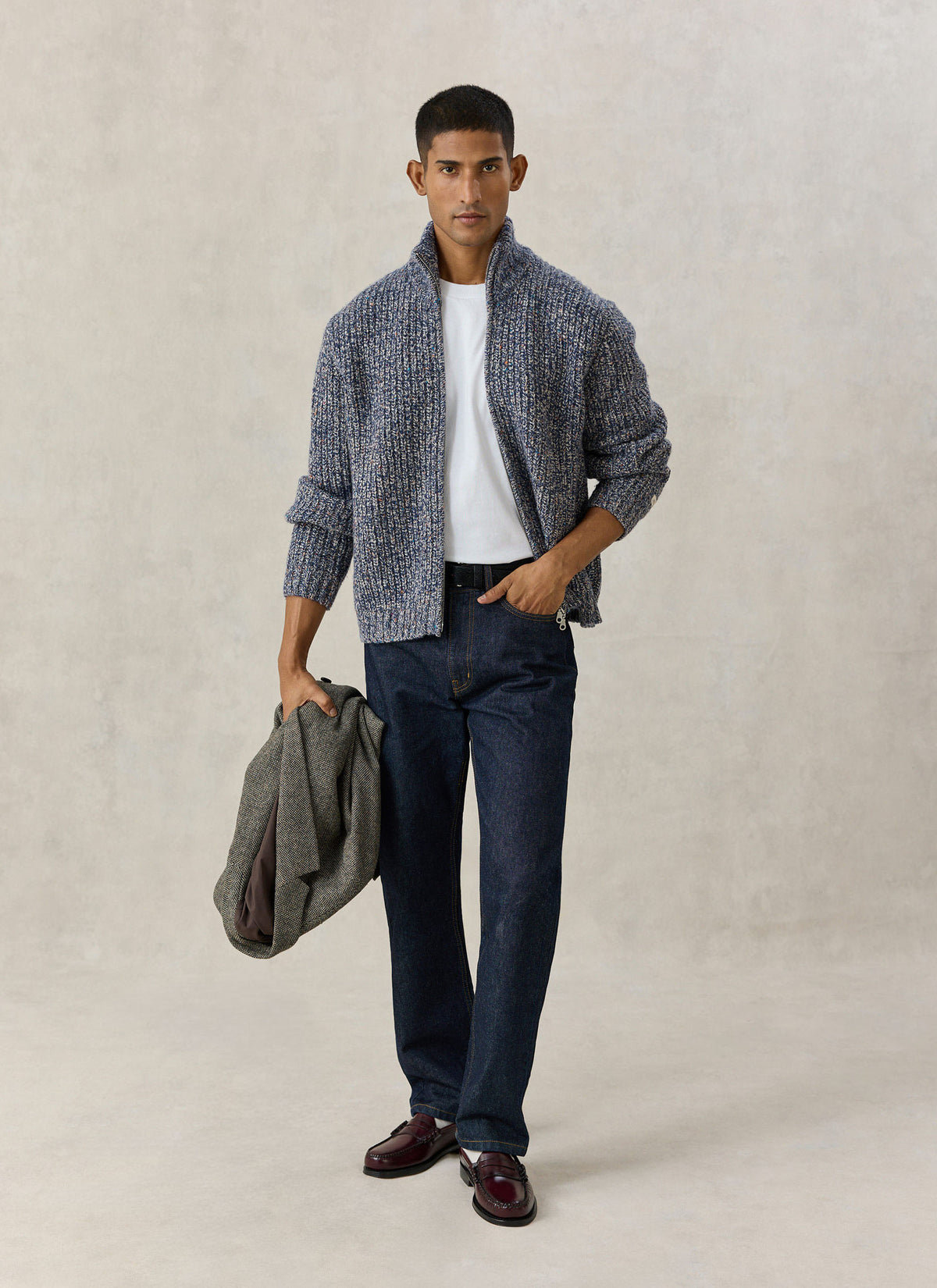 A model wearing the Percival blue fleck alpaca-wool blend zip cardigan over a white tee and dark jeans, holding a jacket.