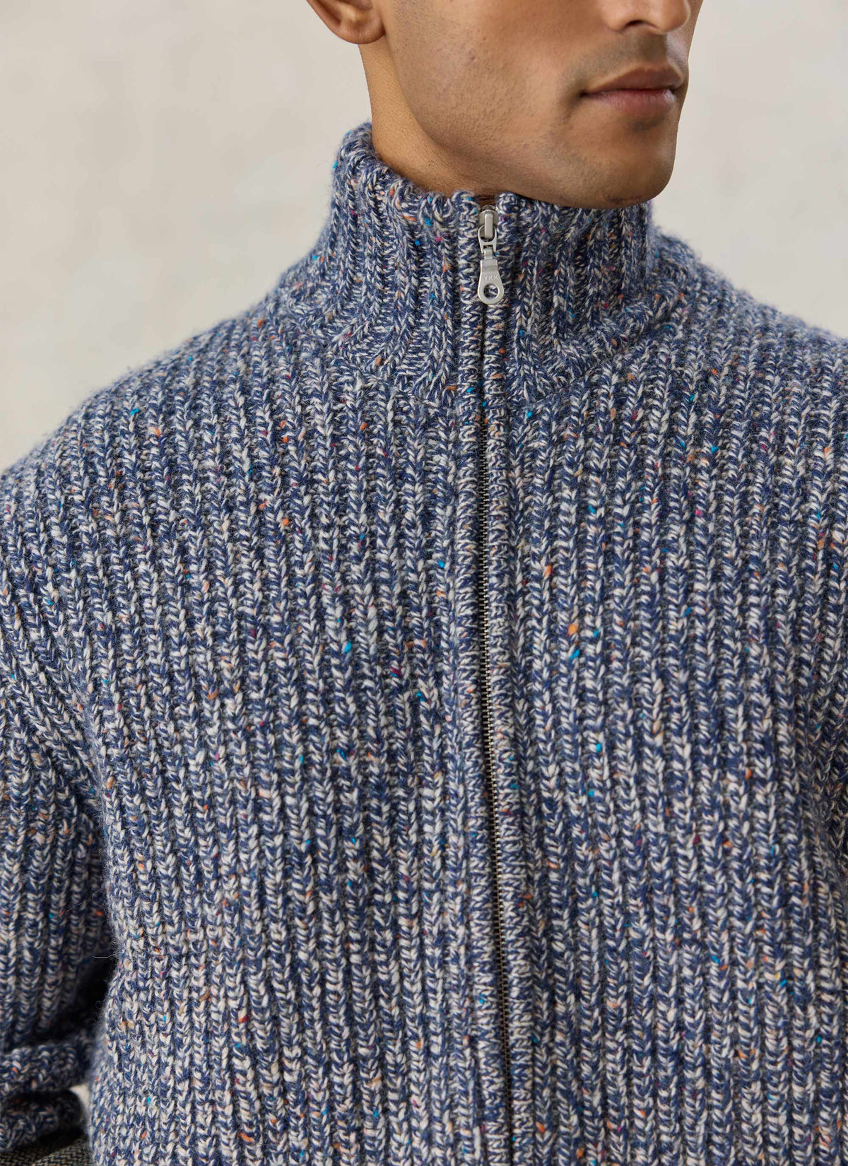 A close-up of the Percival Norton blue fleck zip cardigan, highlighting the chunky ribbed knit and high collar.