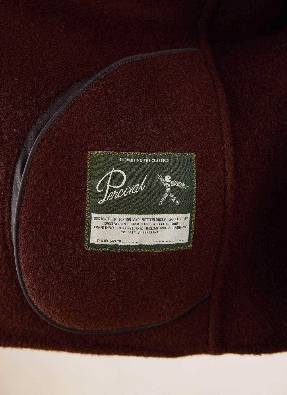 A close-up of the interior brand label inside the brown fleck overshirt from Percival.