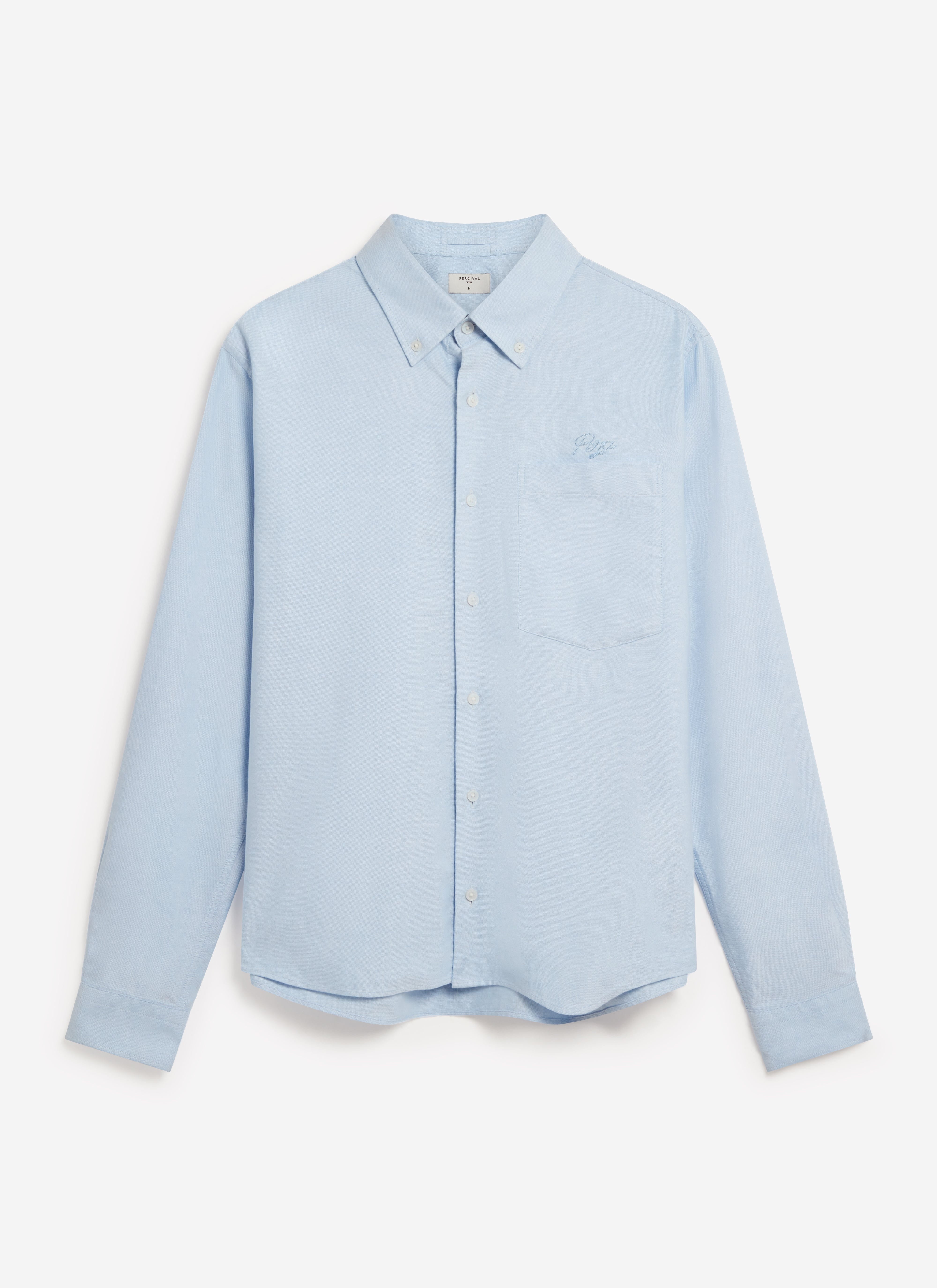 A studio flat lay shot of the Percival men's Oxford Regular Shirt in light blue cotton with chest pocket embroidery.