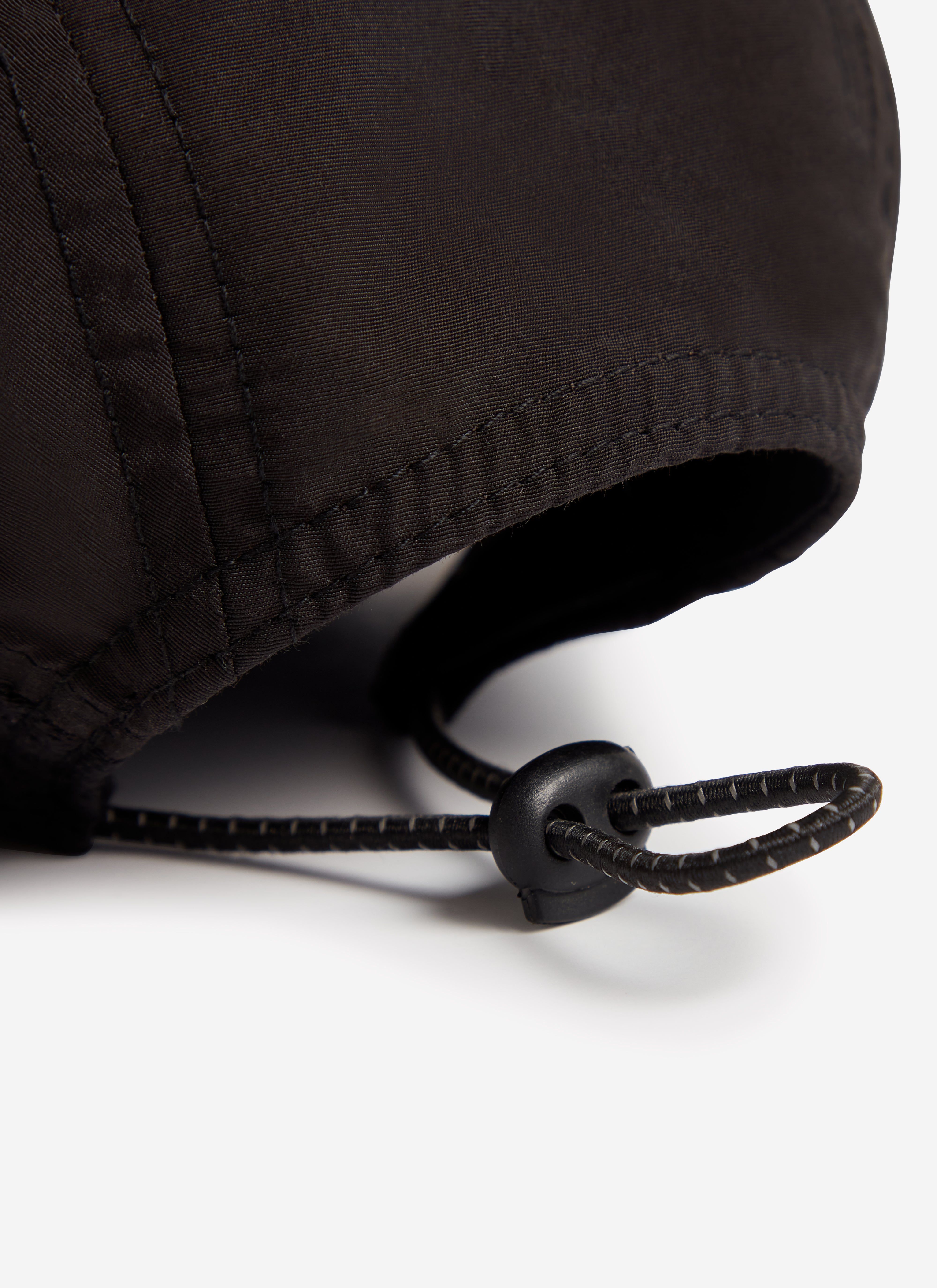 Close-up on the adjustable toggle fastening at the back of the black nylon PCVL cap from Percival.
