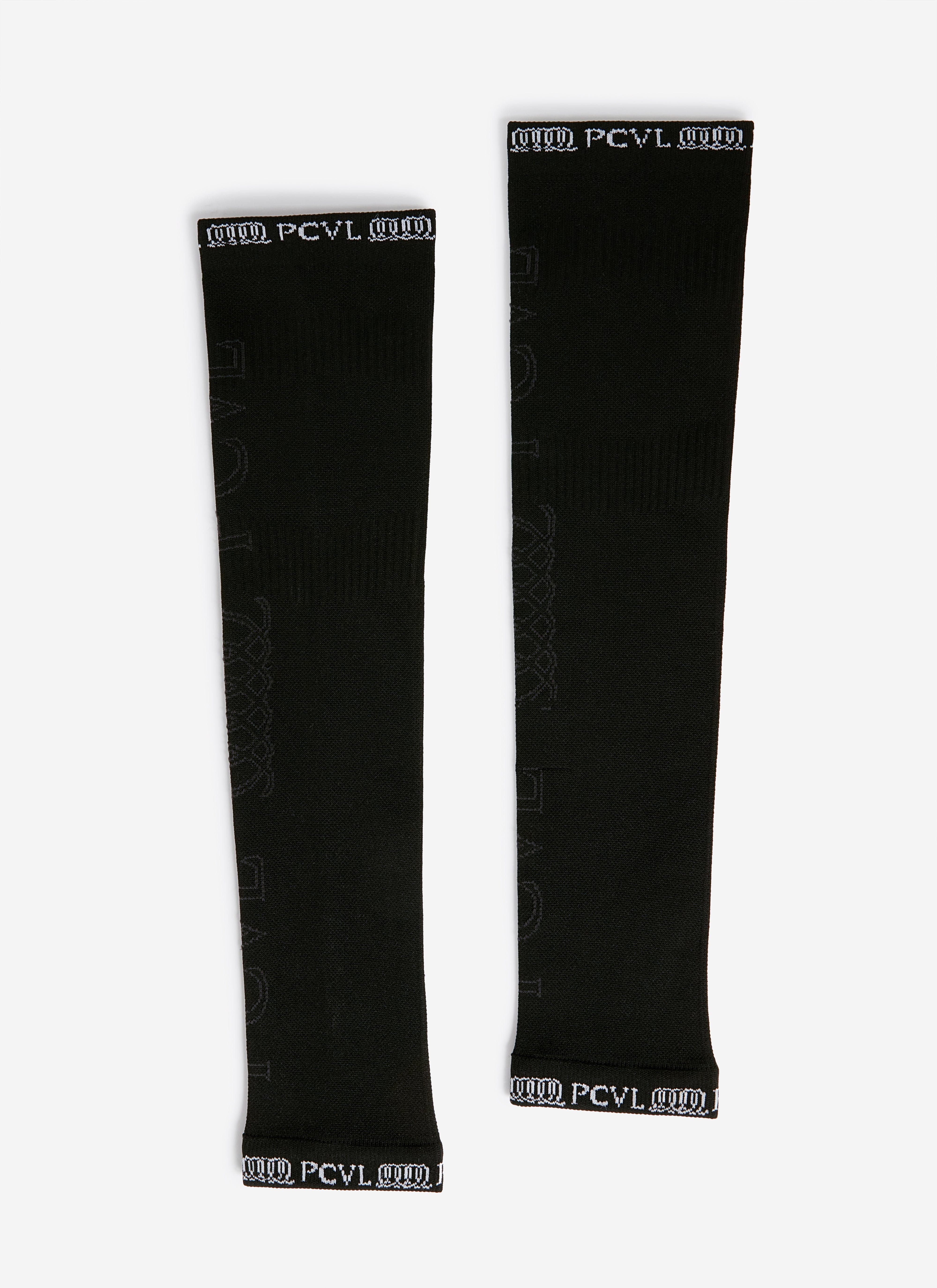 A flat lay of the black PCVL Arm Compression sleeves by Percival, showing the white branded cuffs and subtle jacquard logo.