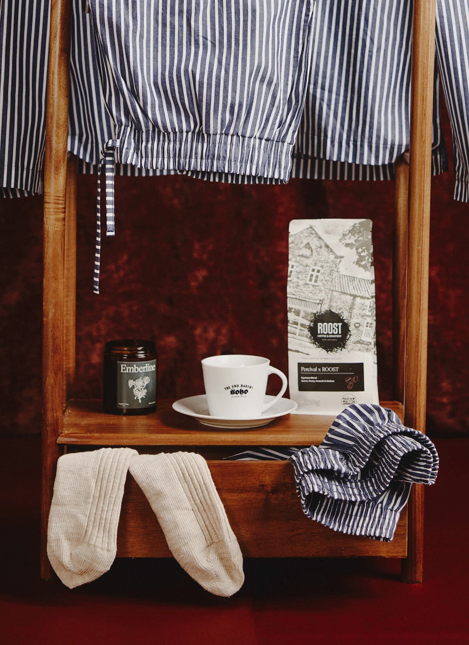 Percival's Roost Espresso Coffee displayed on a wooden stand with striped pyjamas, socks, and a mug for the perfect morning.