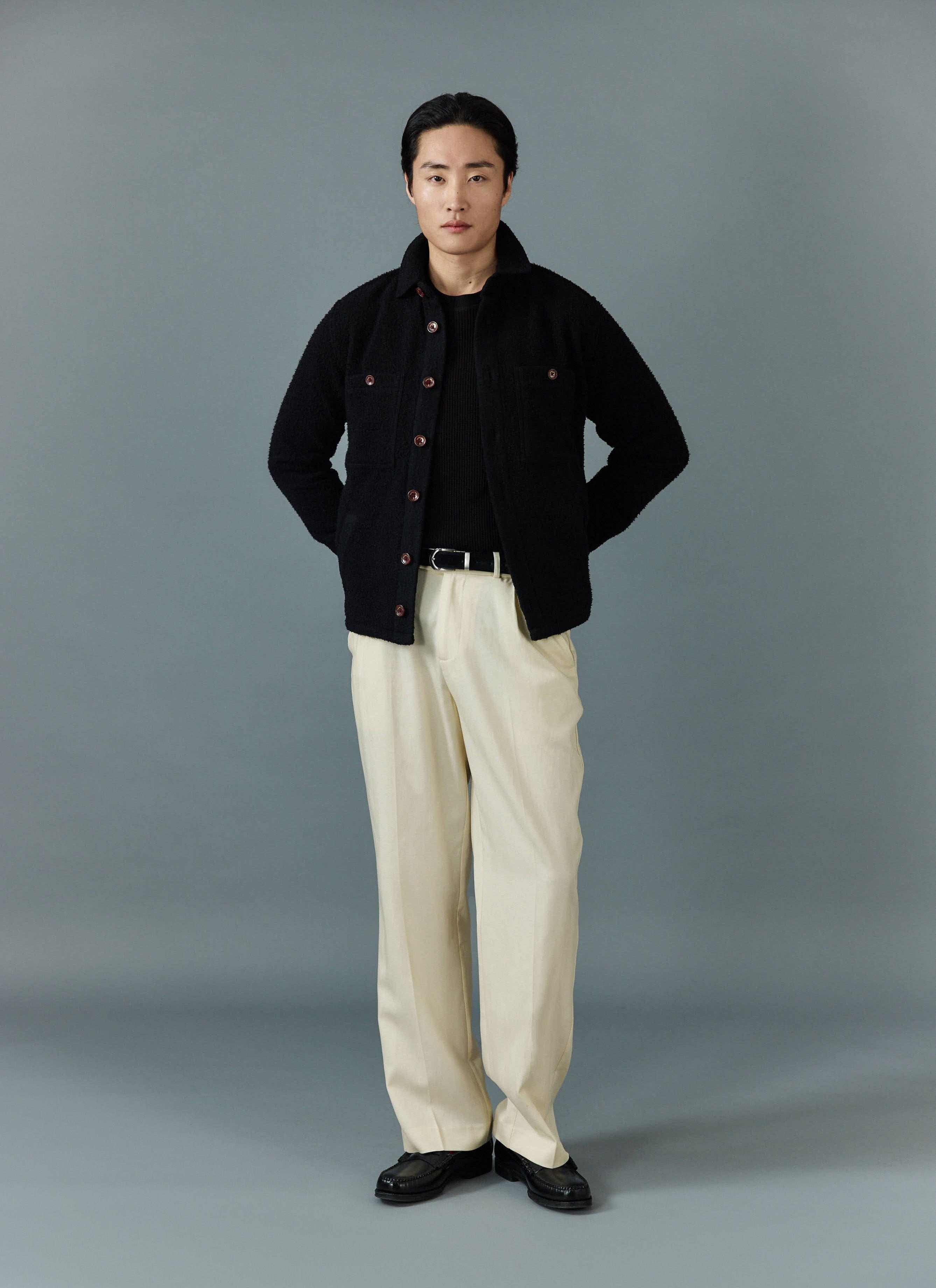 Model wears the Percival black Casentino wool blanket overshirt with a black top, off-white trousers and black loafers.