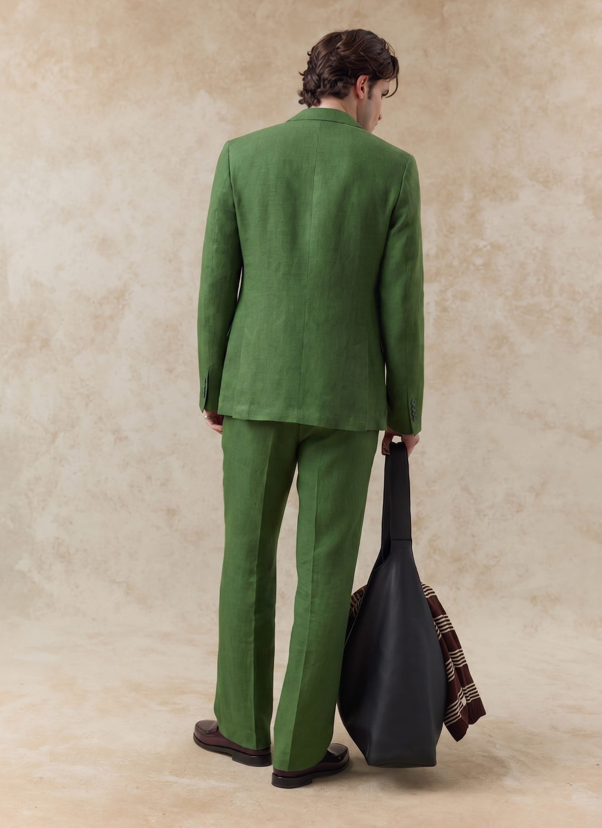 Percival forest green tailored linen blazer and matching trousers shown from behind, styled with a large black leather bag.