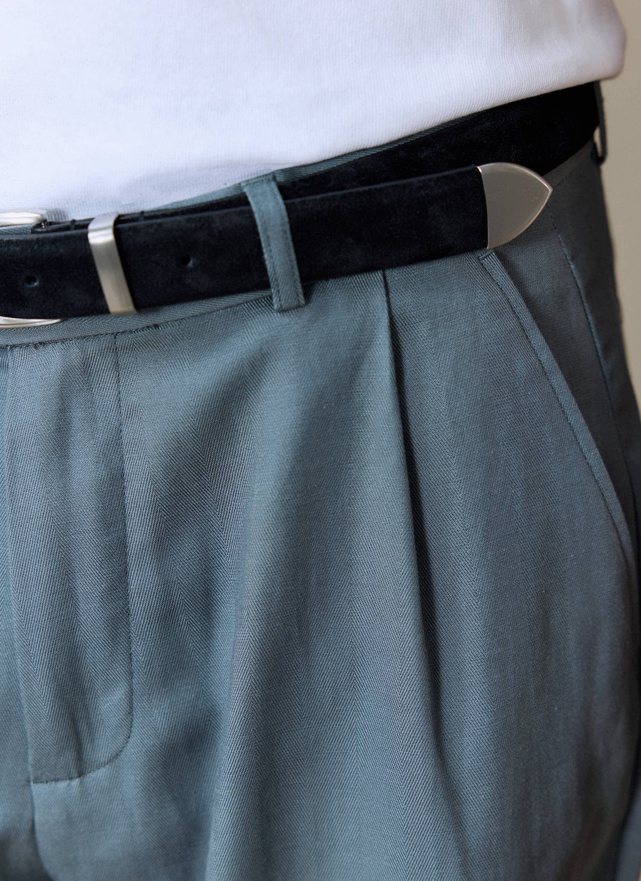 A close-up of the Percival Pleated Leg Trousers in slate blue, showing the fabric texture and pleat detail at the waist.