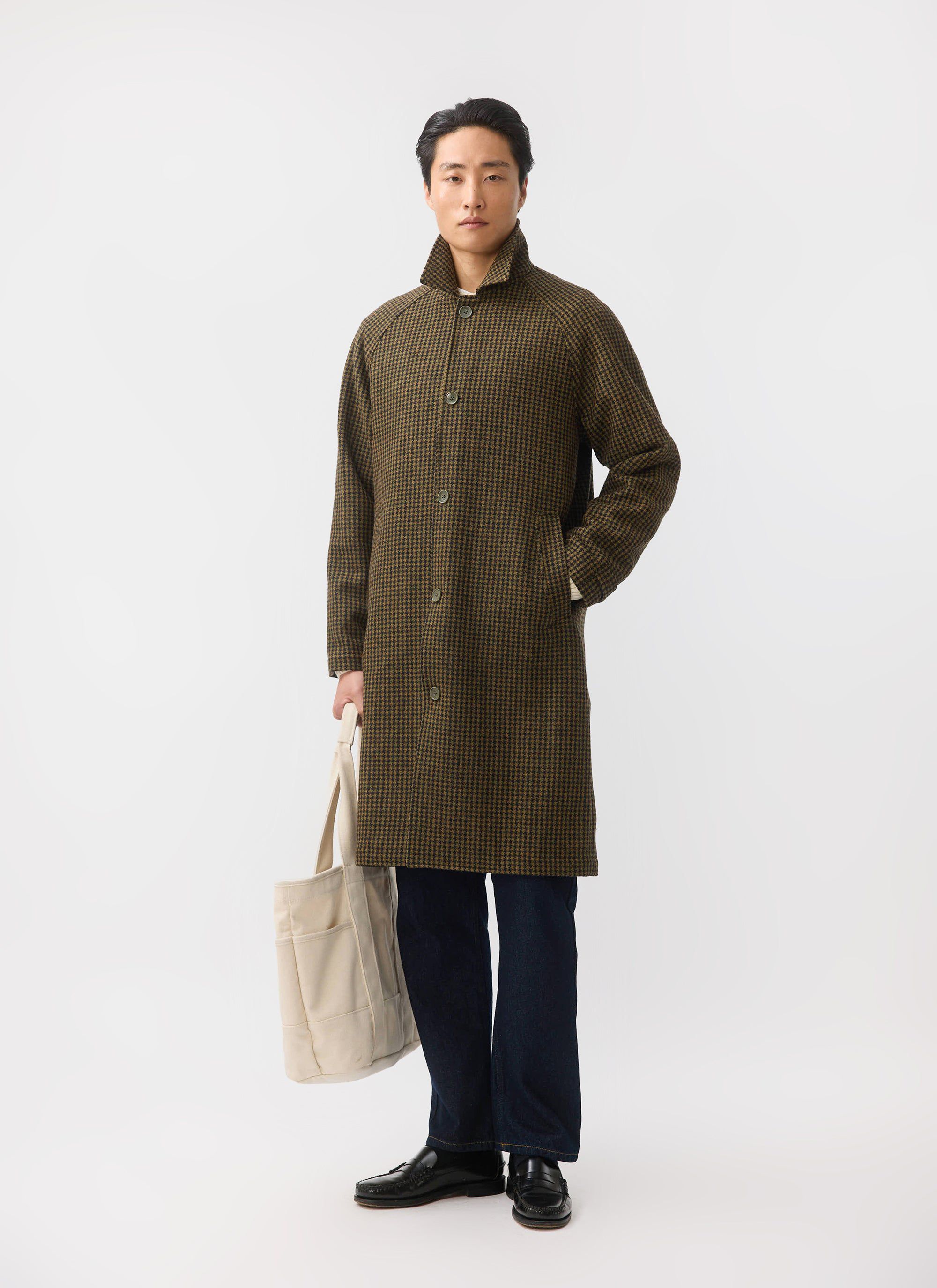 A full-length shot of a man modelling the Percival Dickens Car Coat in Watcher Check, a brown wool houndstooth overcoat.