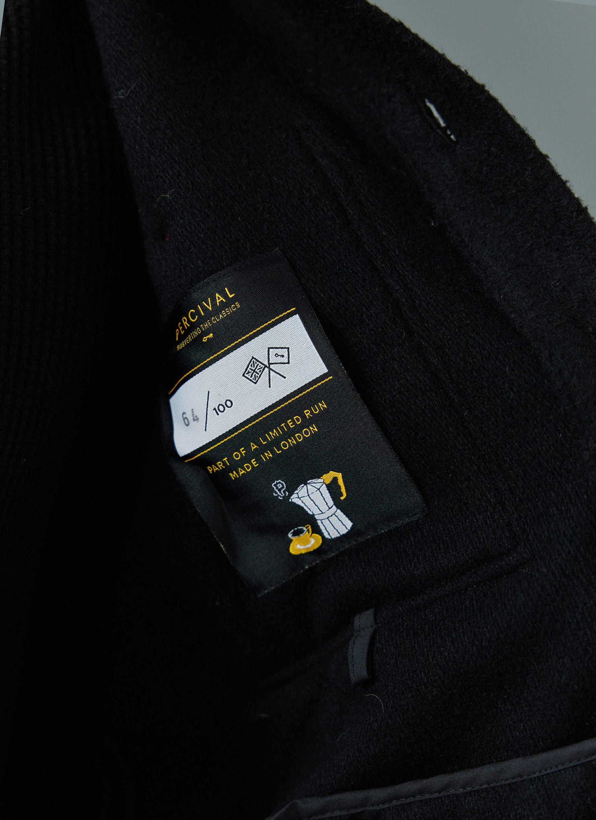 Close up of the Percival label on the black Casentino wool Blanket Overshirt, part of a limited run made in London.