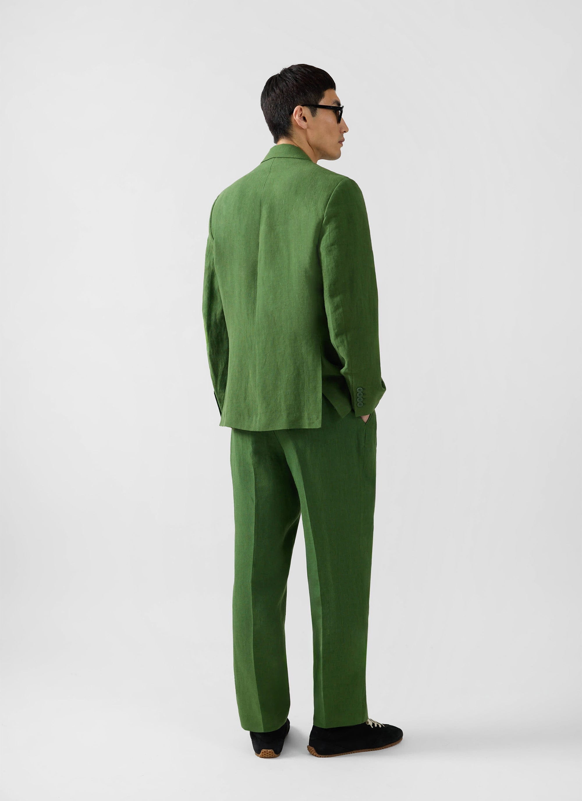 Rear view of a model in the Percival Clifton Double Breasted Blazer and matching trousers in forest green linen.
