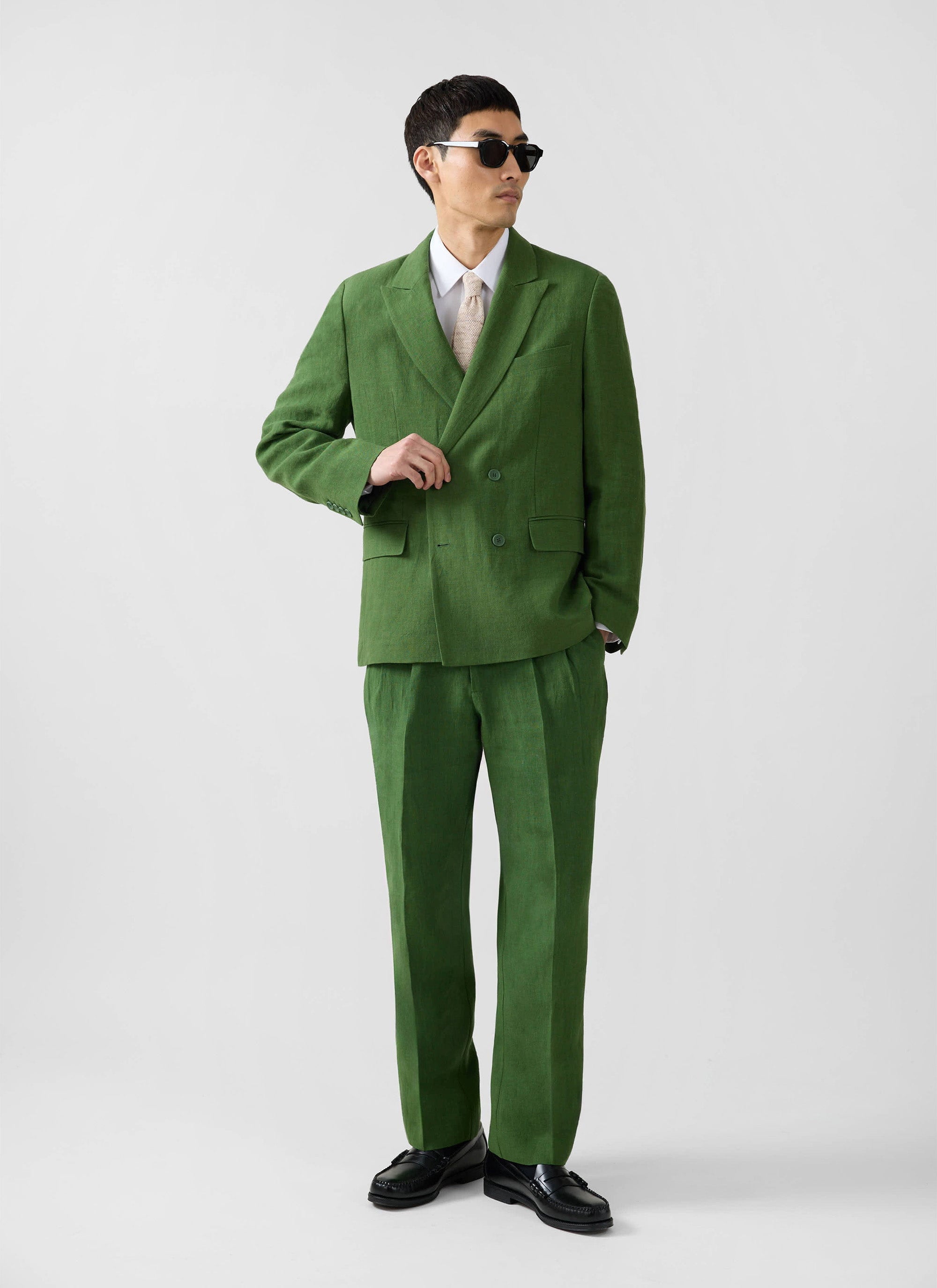 Model wearing the Percival Clifton double-breasted blazer and trousers in forest green linen for a sharp tailored look.