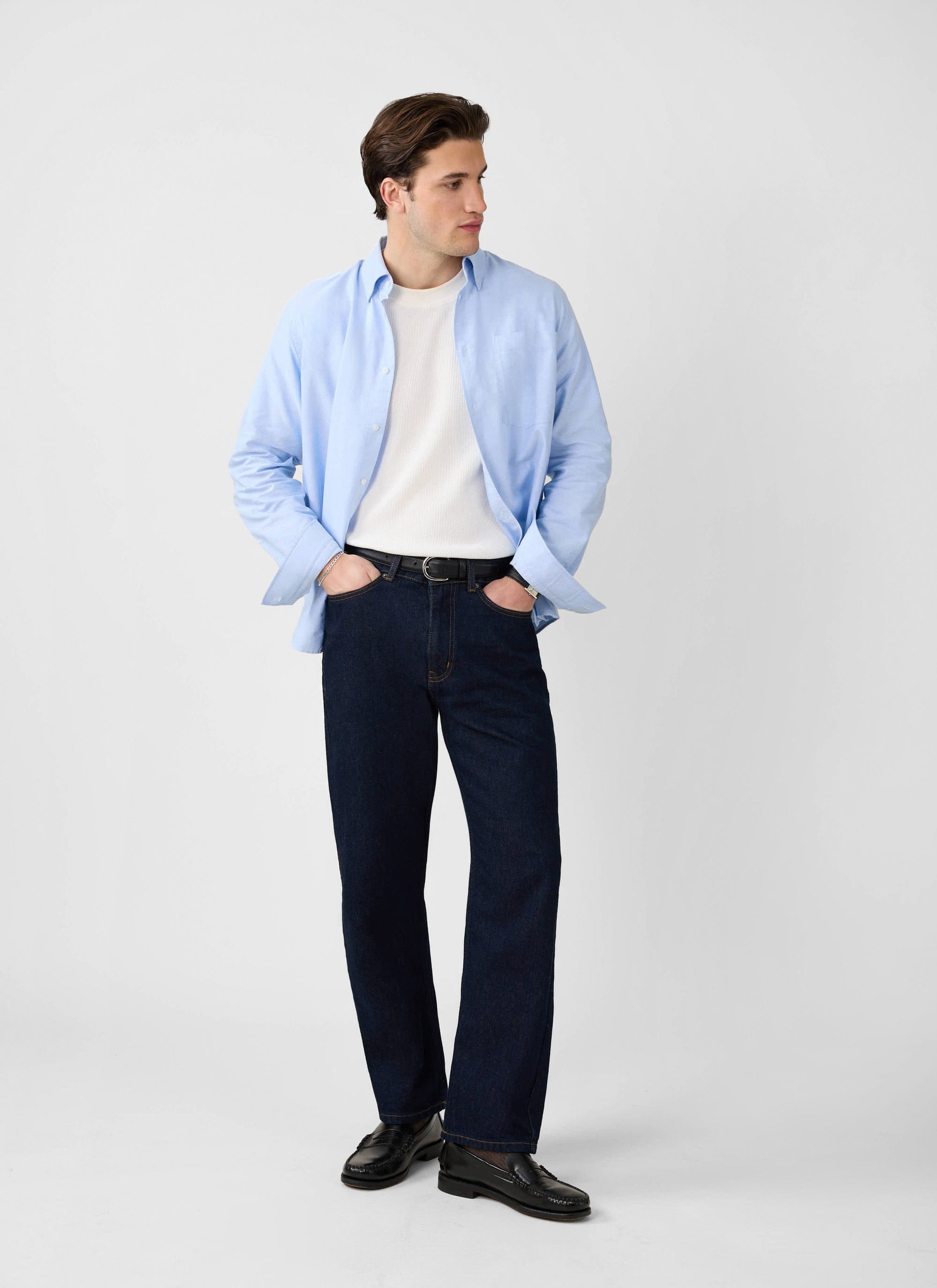 A model wears the white Waffle Short Sleeve T-Shirt from Percival, styled with an open blue shirt and dark jeans.