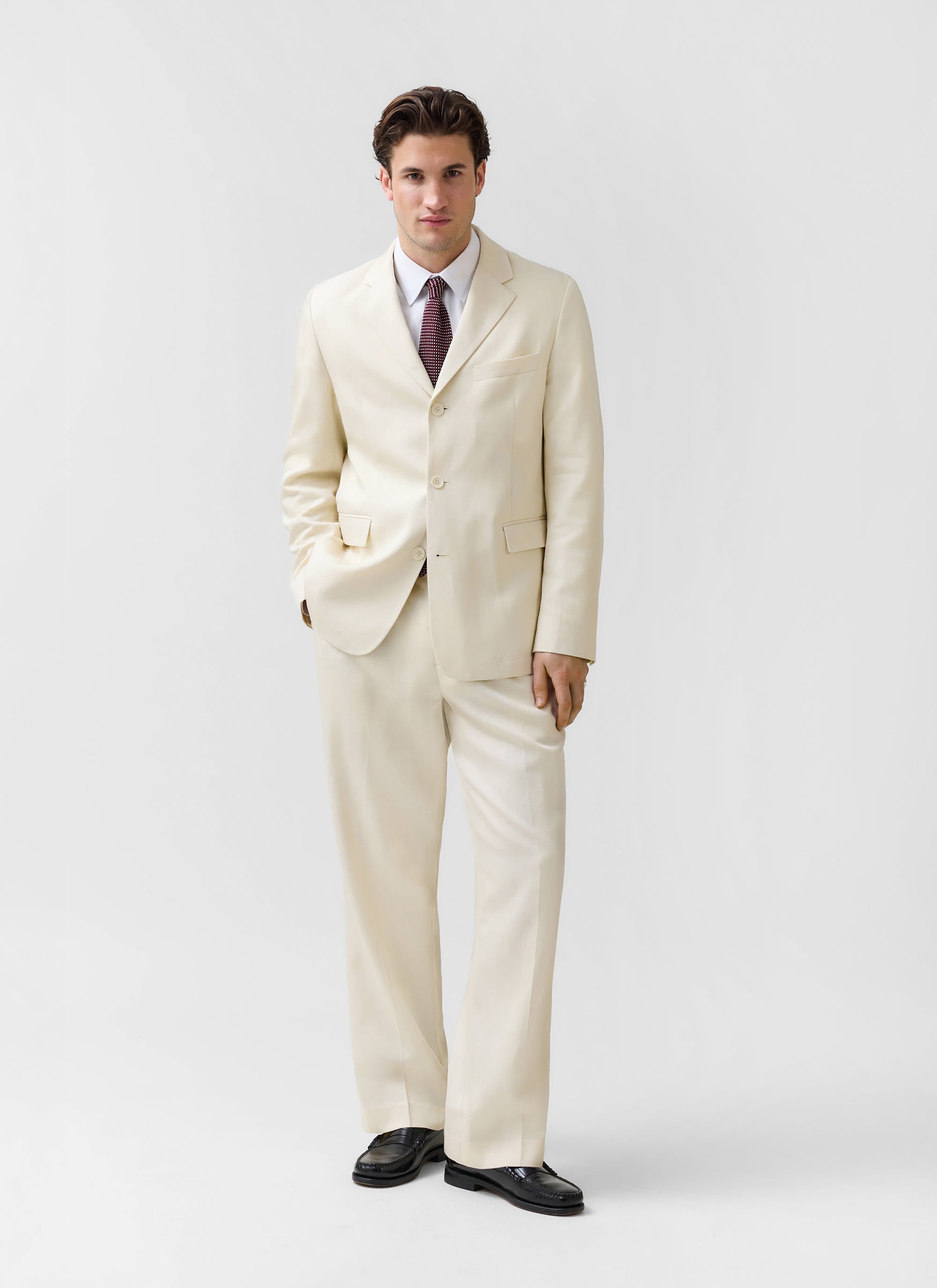 A model wears the Percival Clifton 3 Button Regular Blazer in cream, styled as a full suit in a studio.