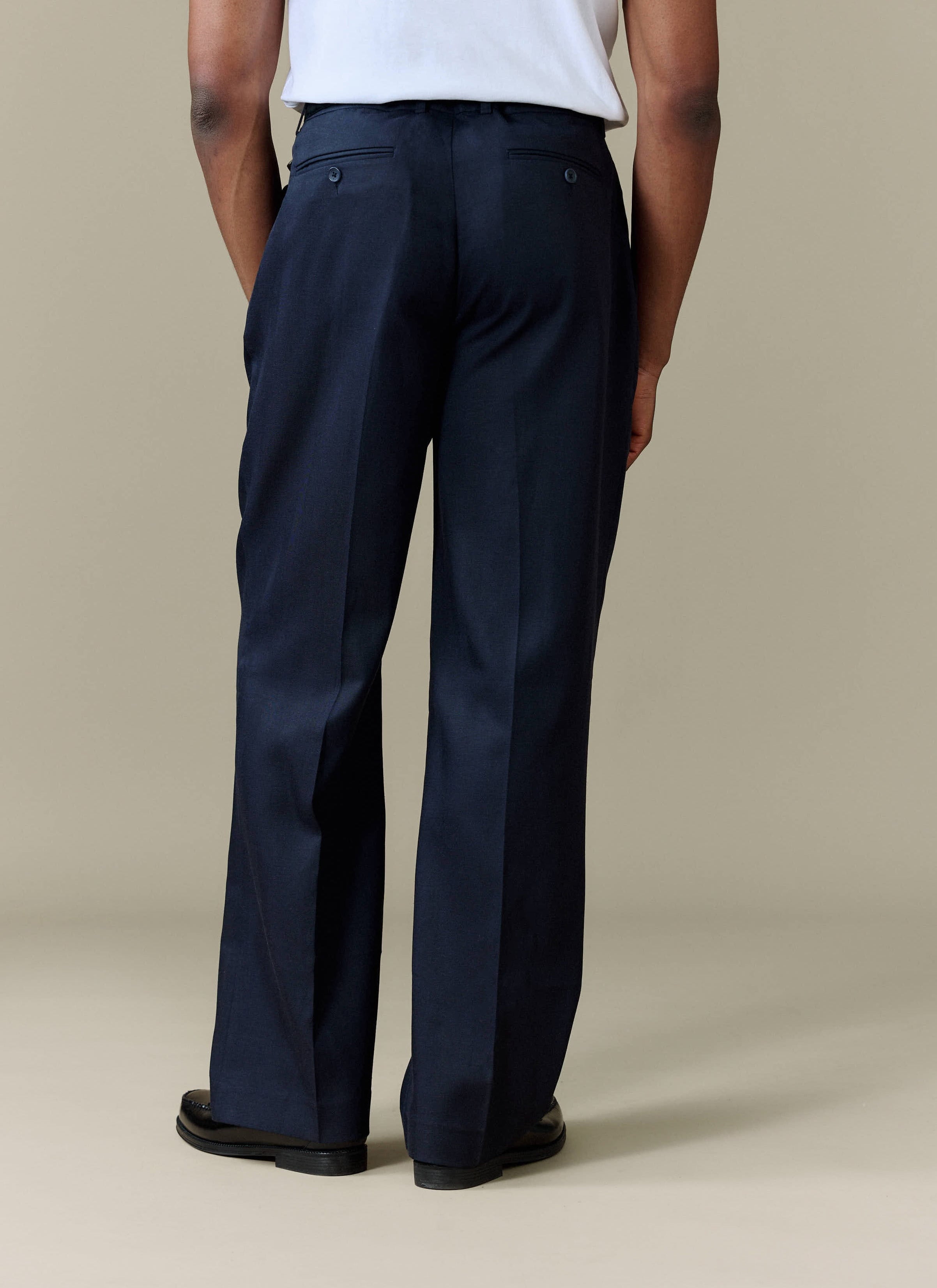 A model from behind showing the relaxed fit of the navy Pleated Leg Trousers from Percival.