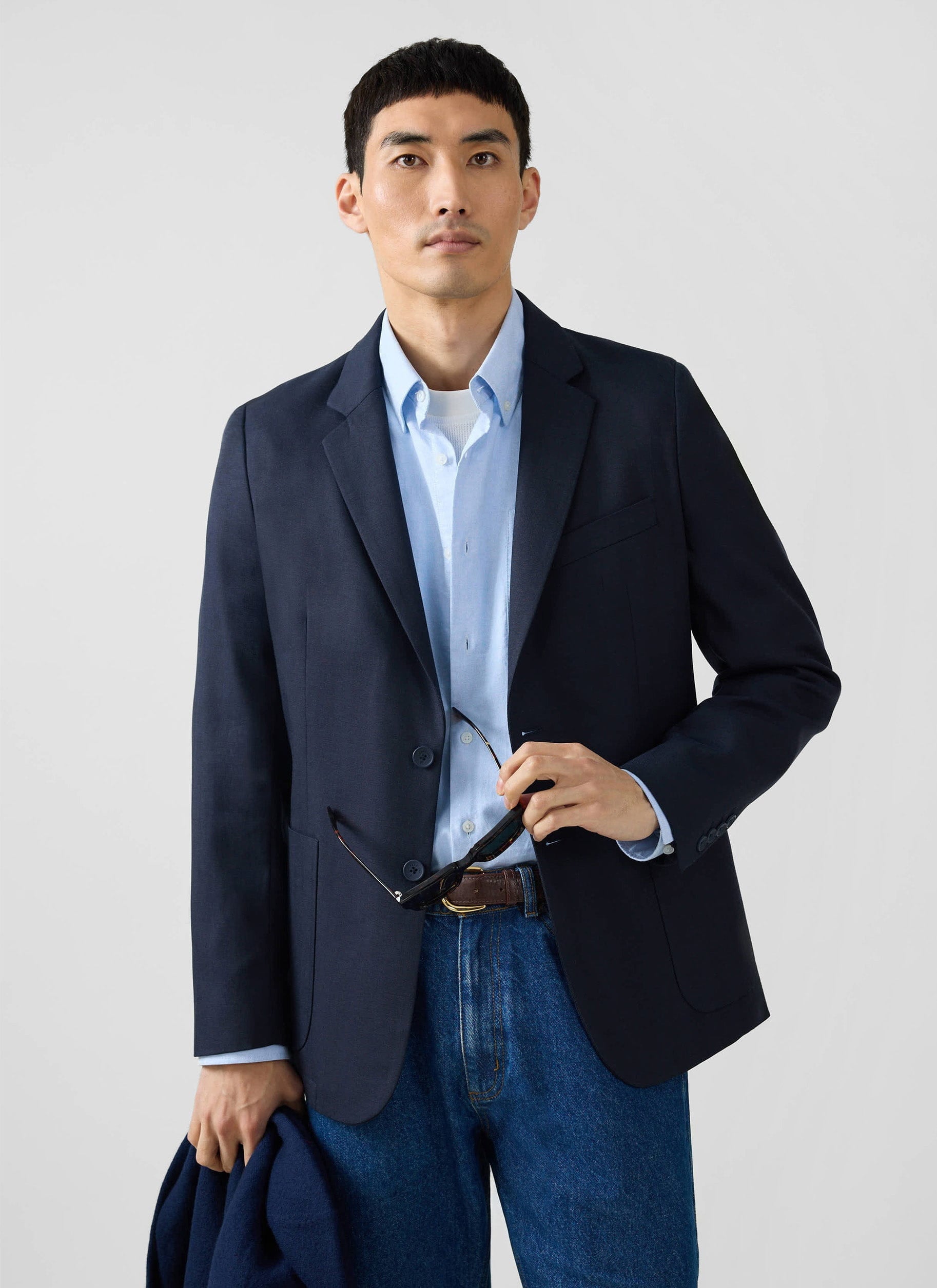 A model wears the navy Lyocell Regular Blazer from Percival, styled with a light blue shirt and classic blue jeans.