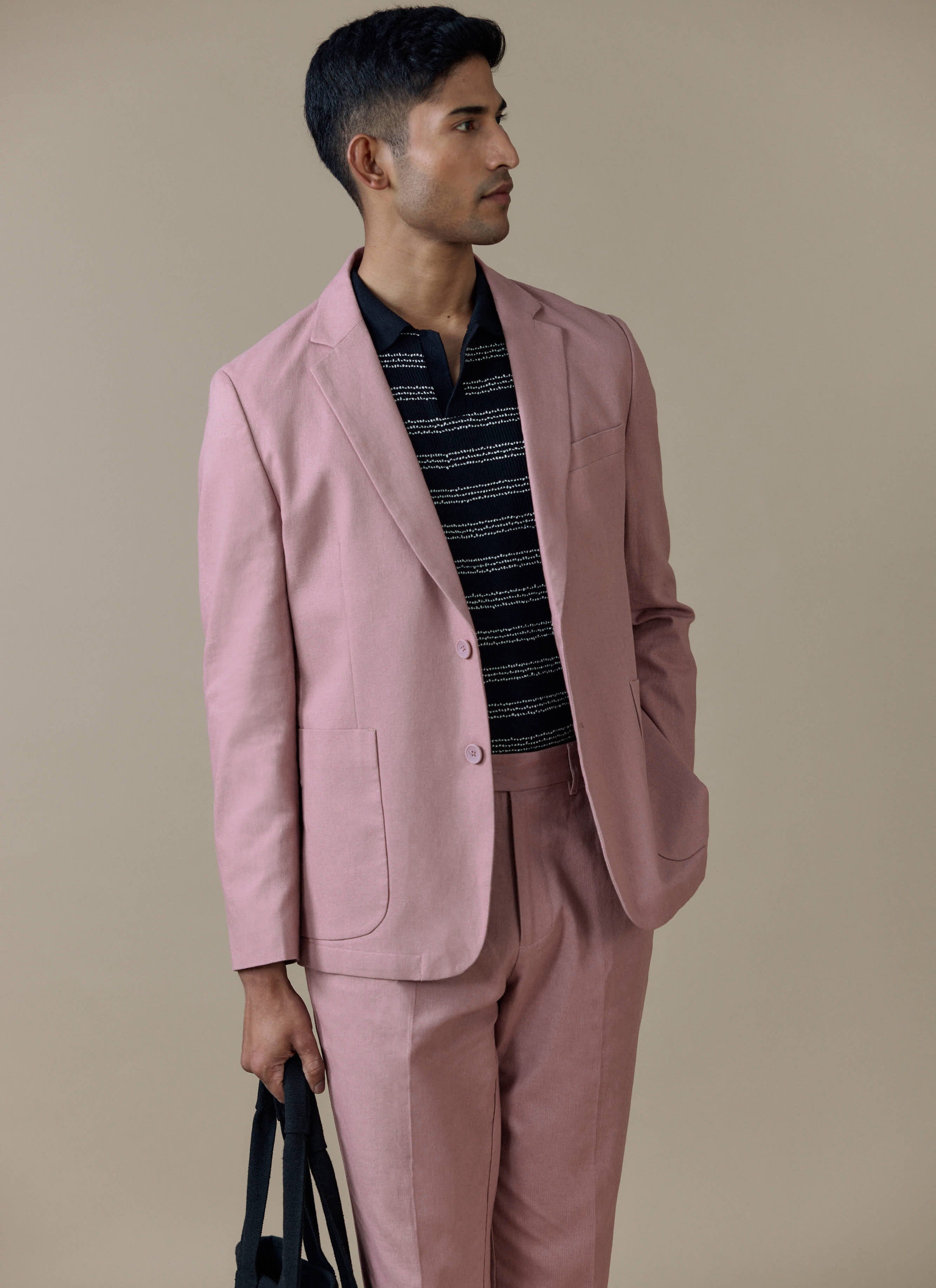 Tailored linen blazer in dusty pink by Percival, styled with matching trousers and a dark patterned polo shirt.