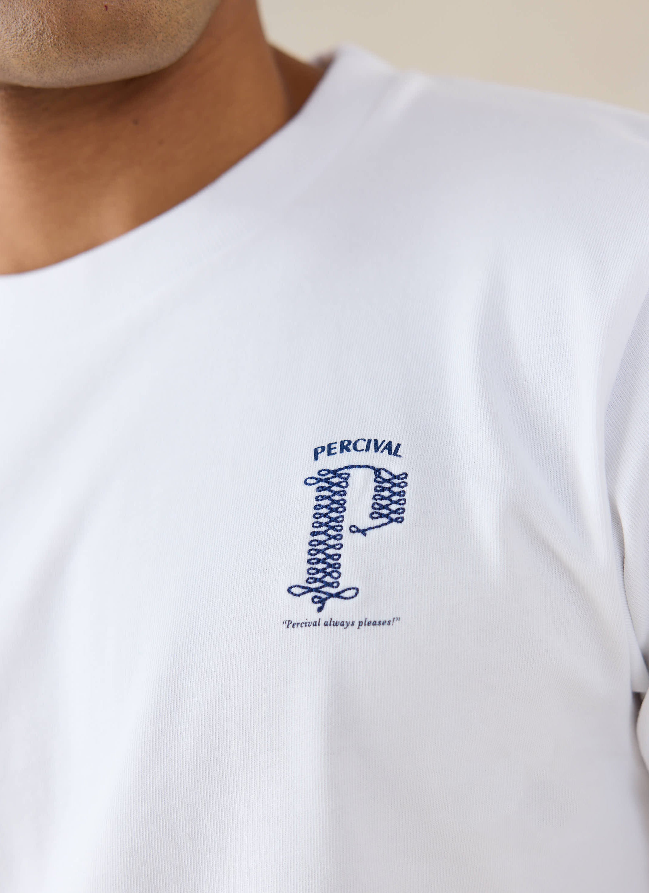 A close-up of the white organic cotton Cyril T-shirt from Percival, highlighting the blue chest graphic and branding.