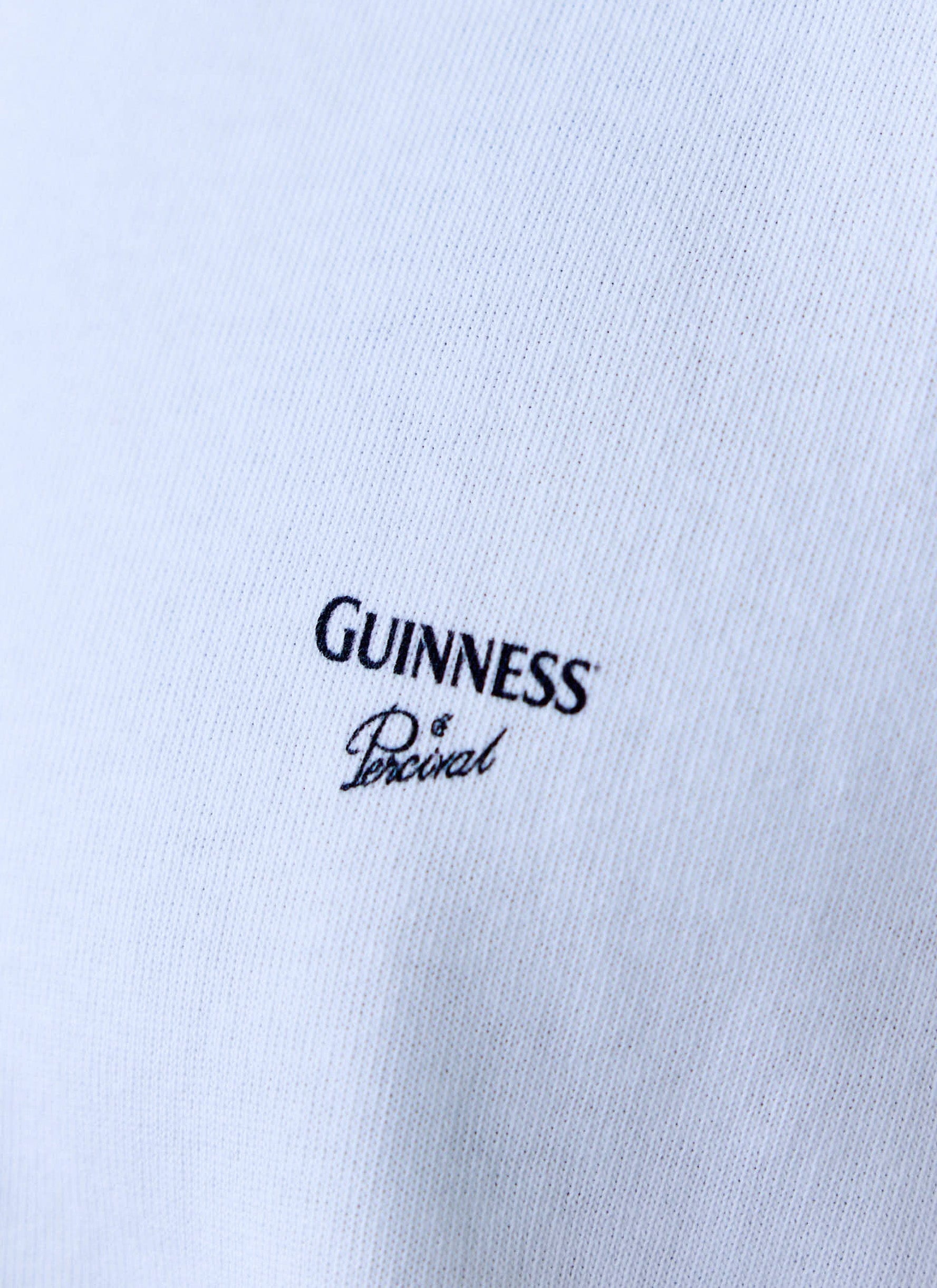 A close-up of the black Guinness and Percival logo on the chest of the white Guinness x Percival Oversized T-Shirt.