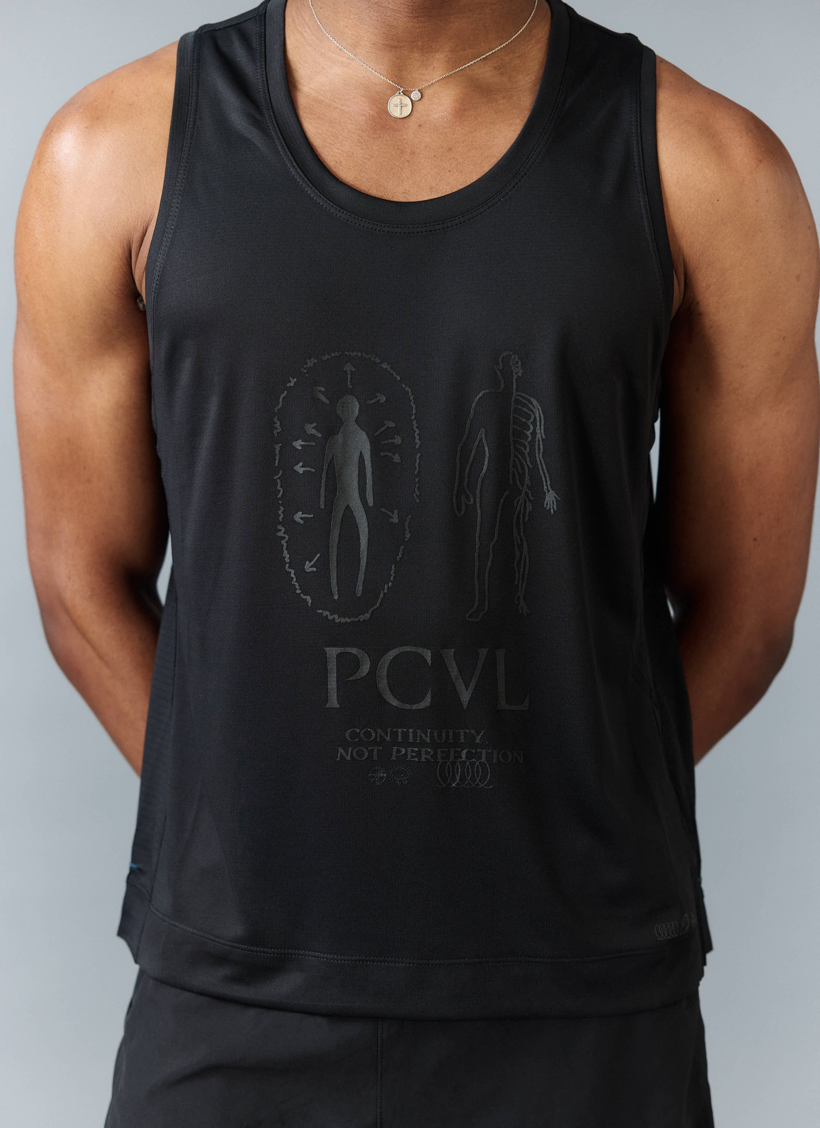A close-up of the tonal chest artwork on the black PCVL Performance Vest by Percival, worn by a model.