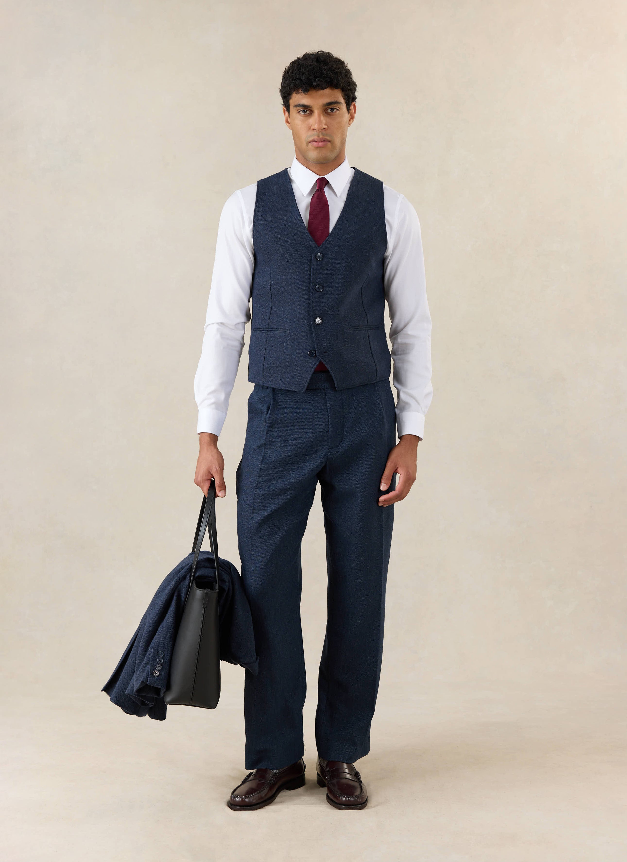 A model wears the Percival Navy Herringbone Wool Stanley Tailored Waistcoat.
