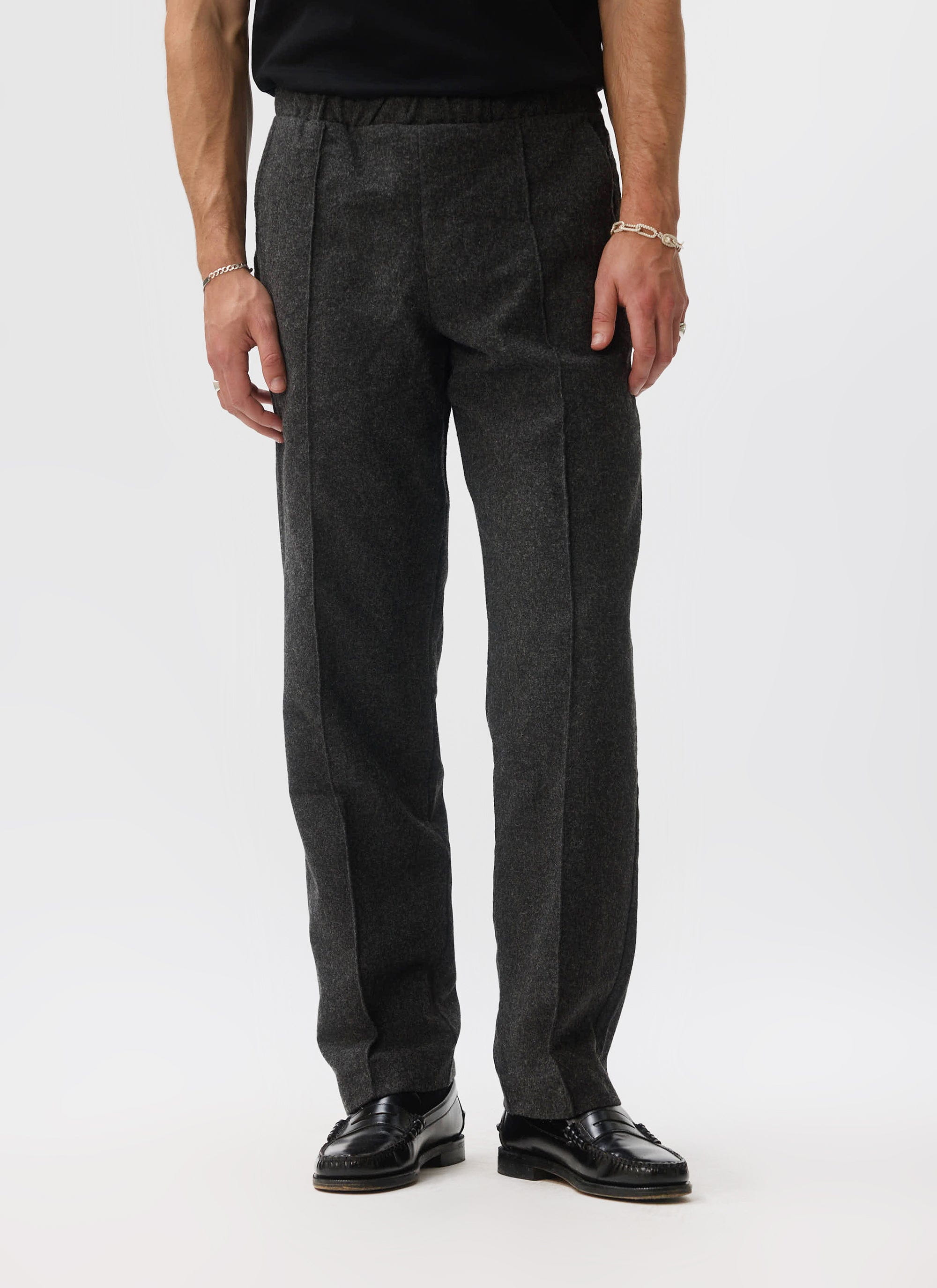A man models the Percival Caxton Smart Trousers in black brushed wool, shot front-on in a studio.