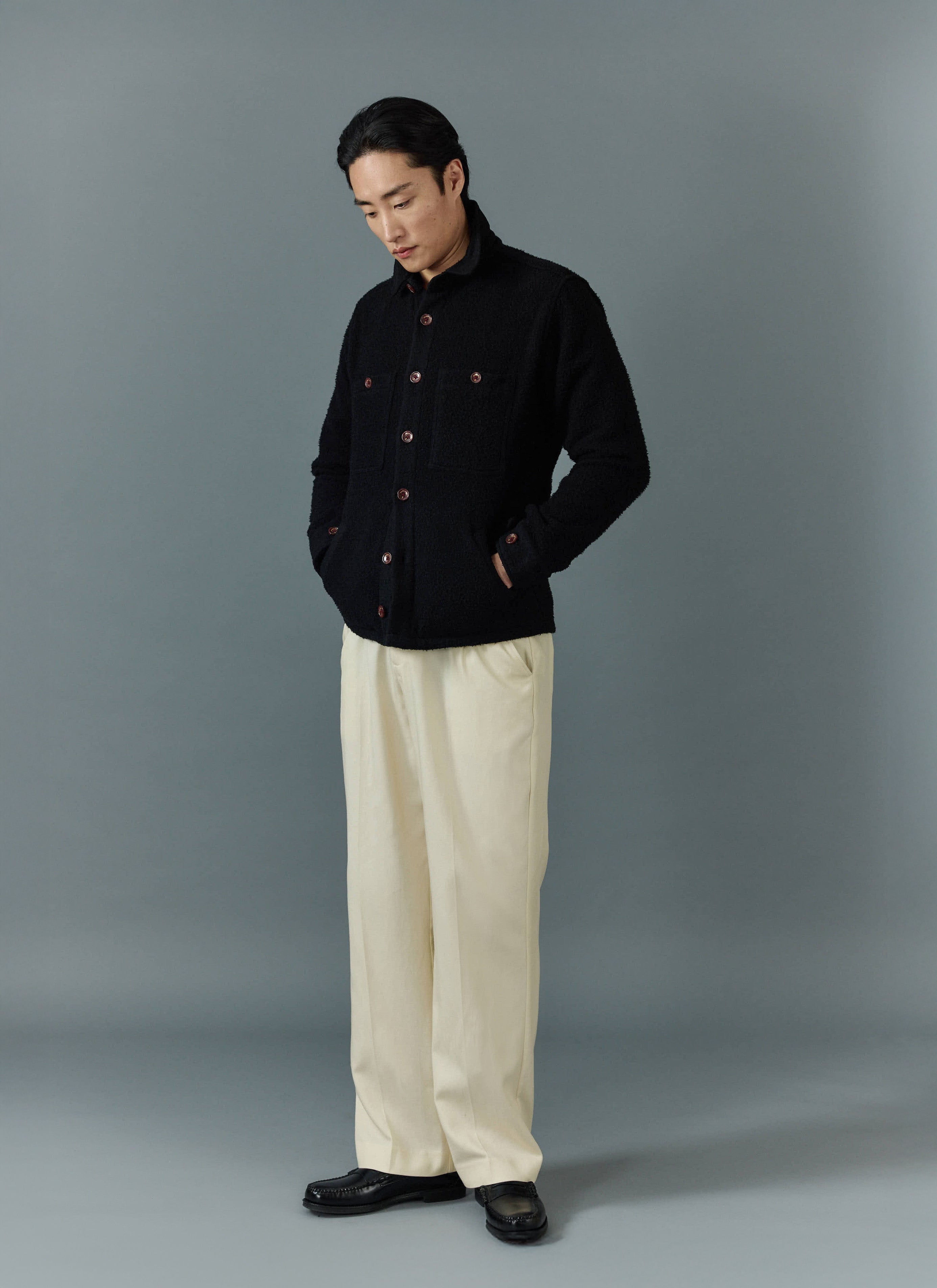A model wears the black Percival Blanket Overshirt in Casentino wool, styled with cream trousers and black loafers.