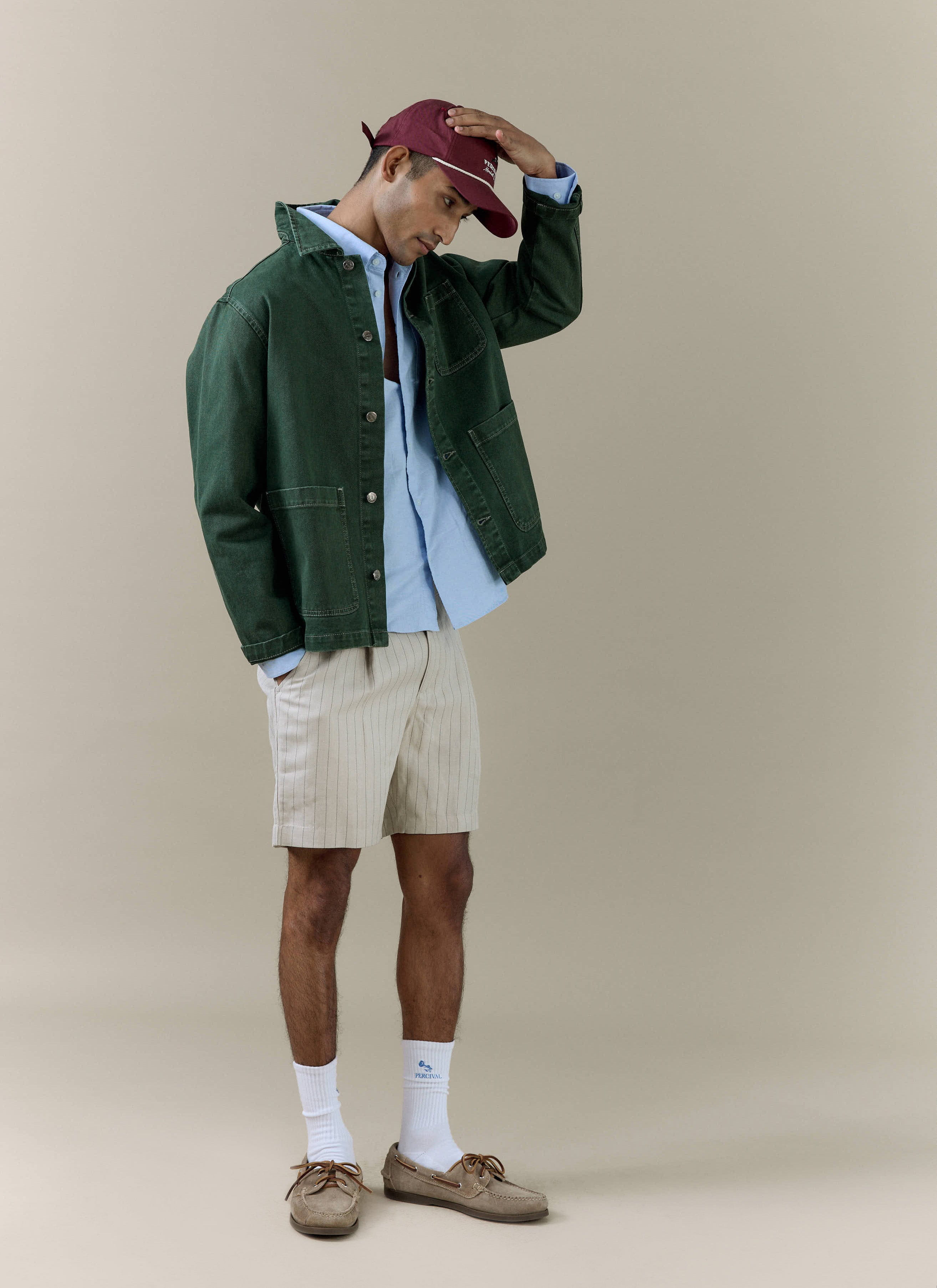 A model wears the Percival cream striped tailored linen blend shorts, styled with a green jacket and blue shirt.