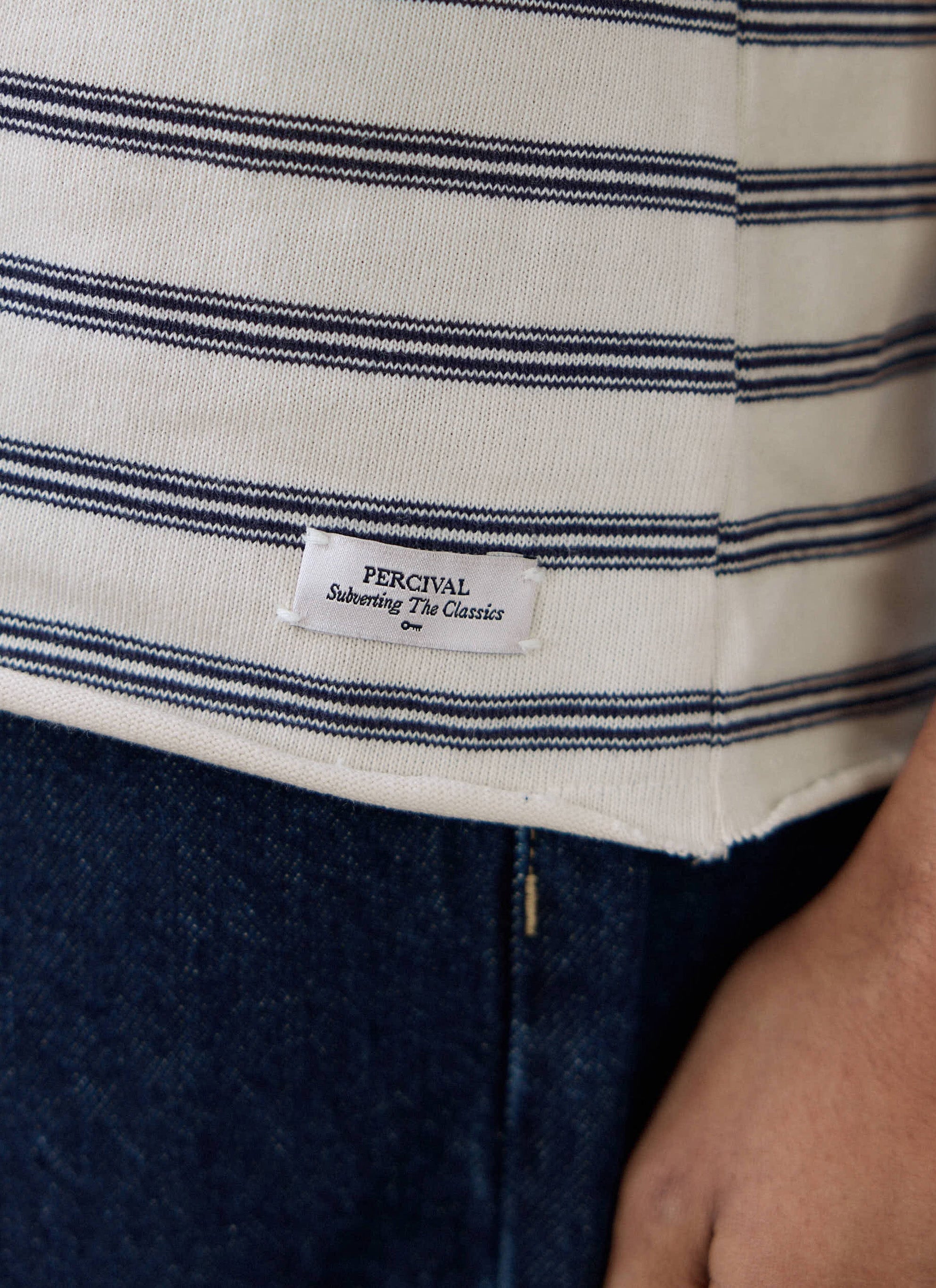 Close-up of the woven label on the raw hem of the Percival Arlo Raw Hem Breton T Shirt in white stripe.