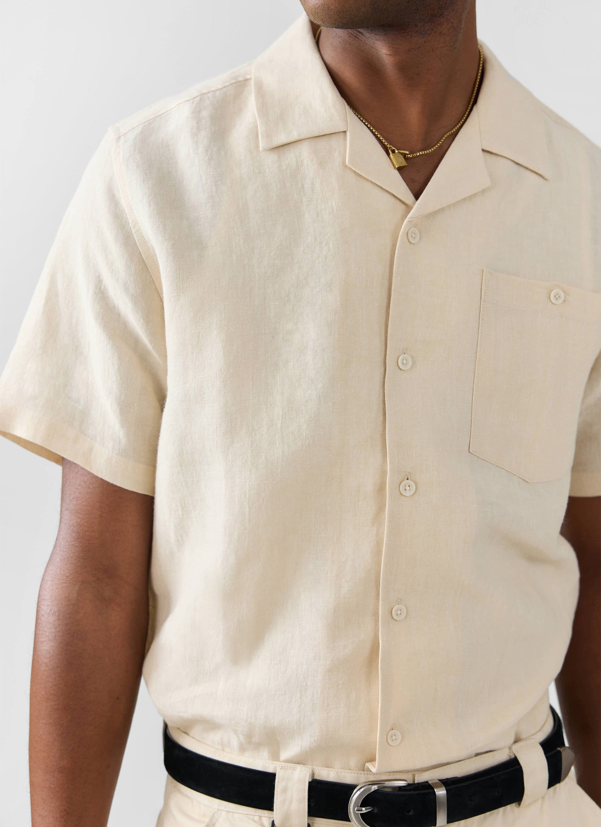 Close up of a model wearing the Percival cream linen Short Sleeve Cuban Shirt, showing the collar and chest pocket detail.