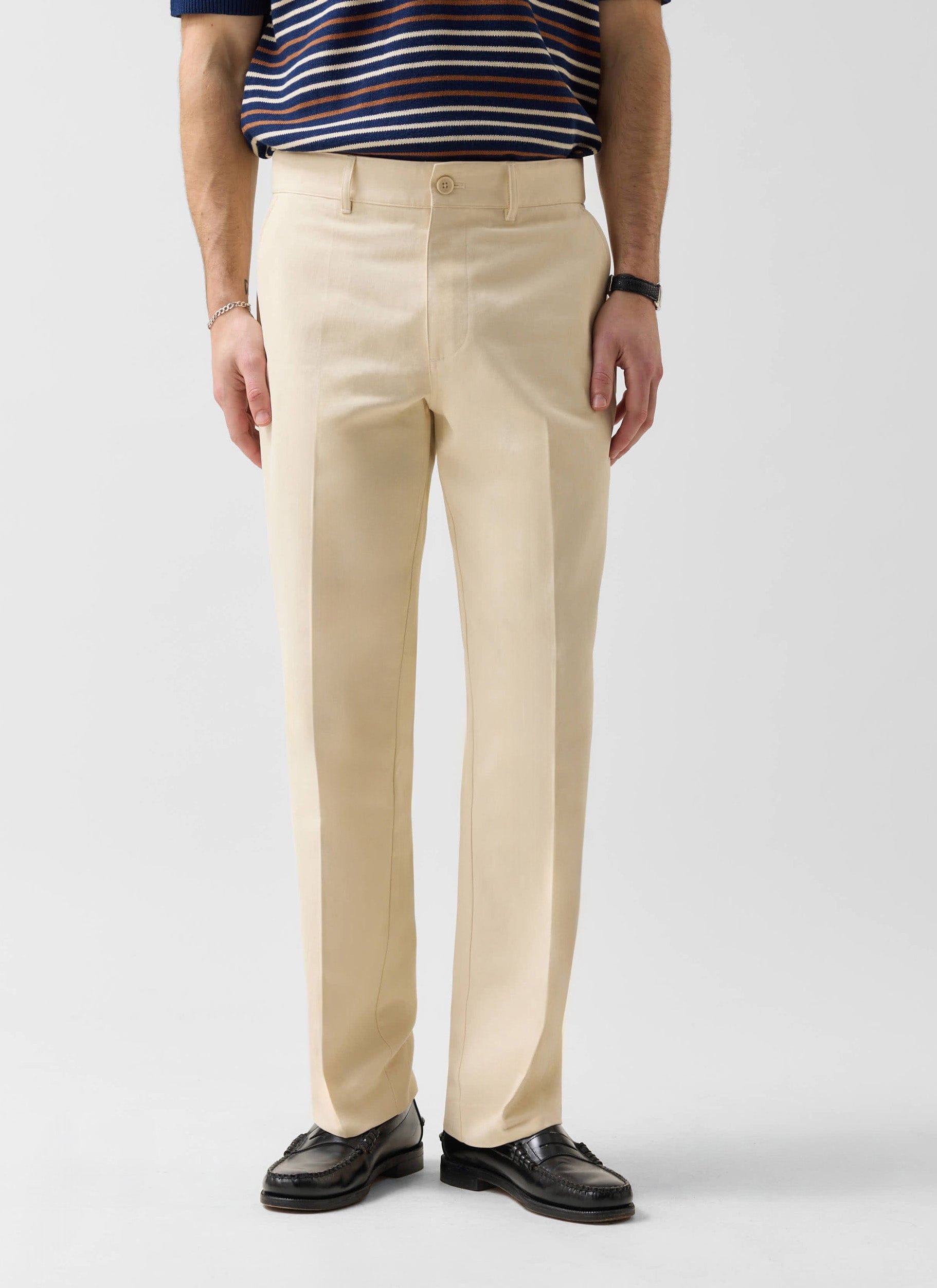 A model wears the Percival Straight Leg Chino in ecru, paired with a striped top and black loafers on a white background.
