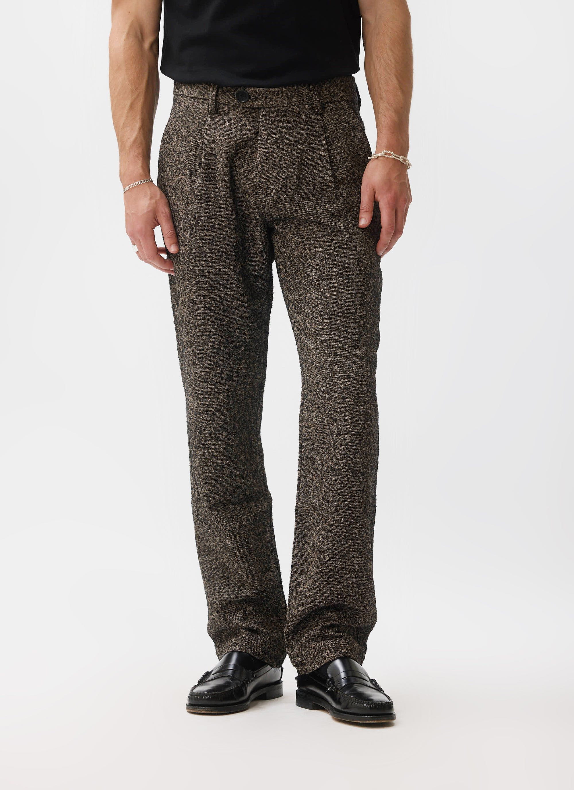A front view of a model wearing the Percival Blyton Trousers in grey, showing the pleated front and textured nep fabric.
