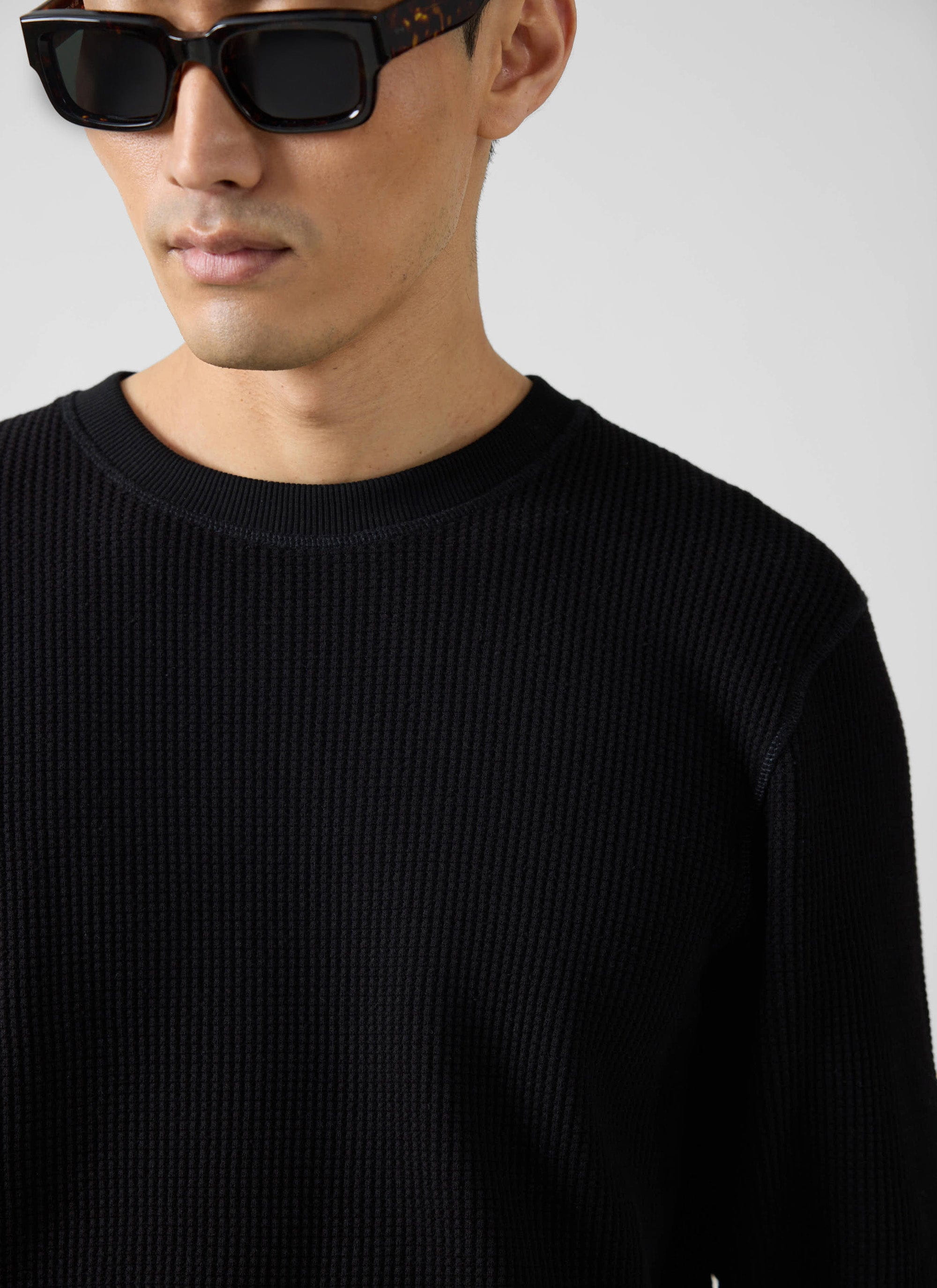Close-up of a model wearing the Percival Waffle Long Sleeve T Shirt in black, showing the textured knit detail.