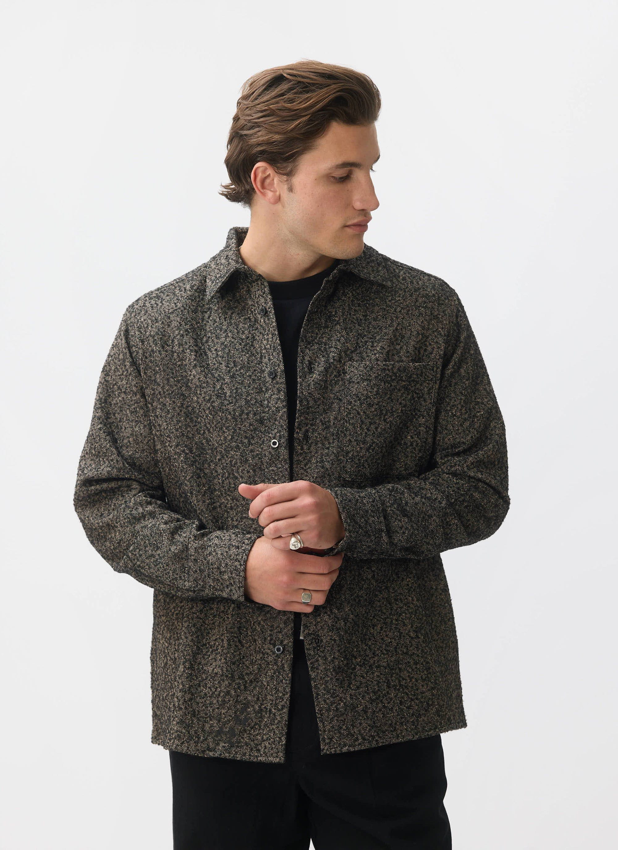 A man models the Percival Blyton Long Sleeve Shirt in nep grey, adjusting his cuff against a white background.