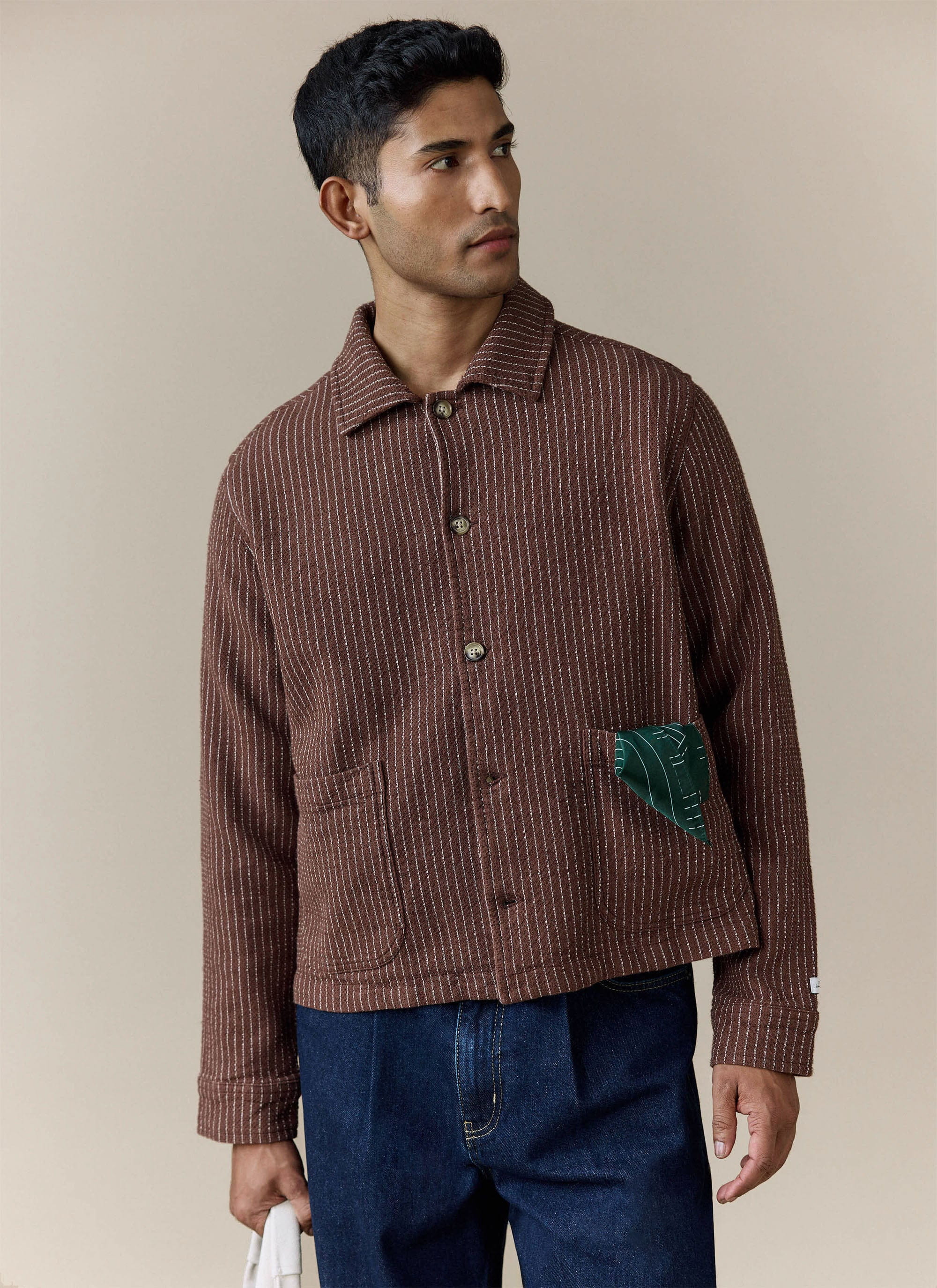 A model wears the Percival Sorrento Boxy Overshirt in brown, a textured linen-blend jacket with vertical white stitching.