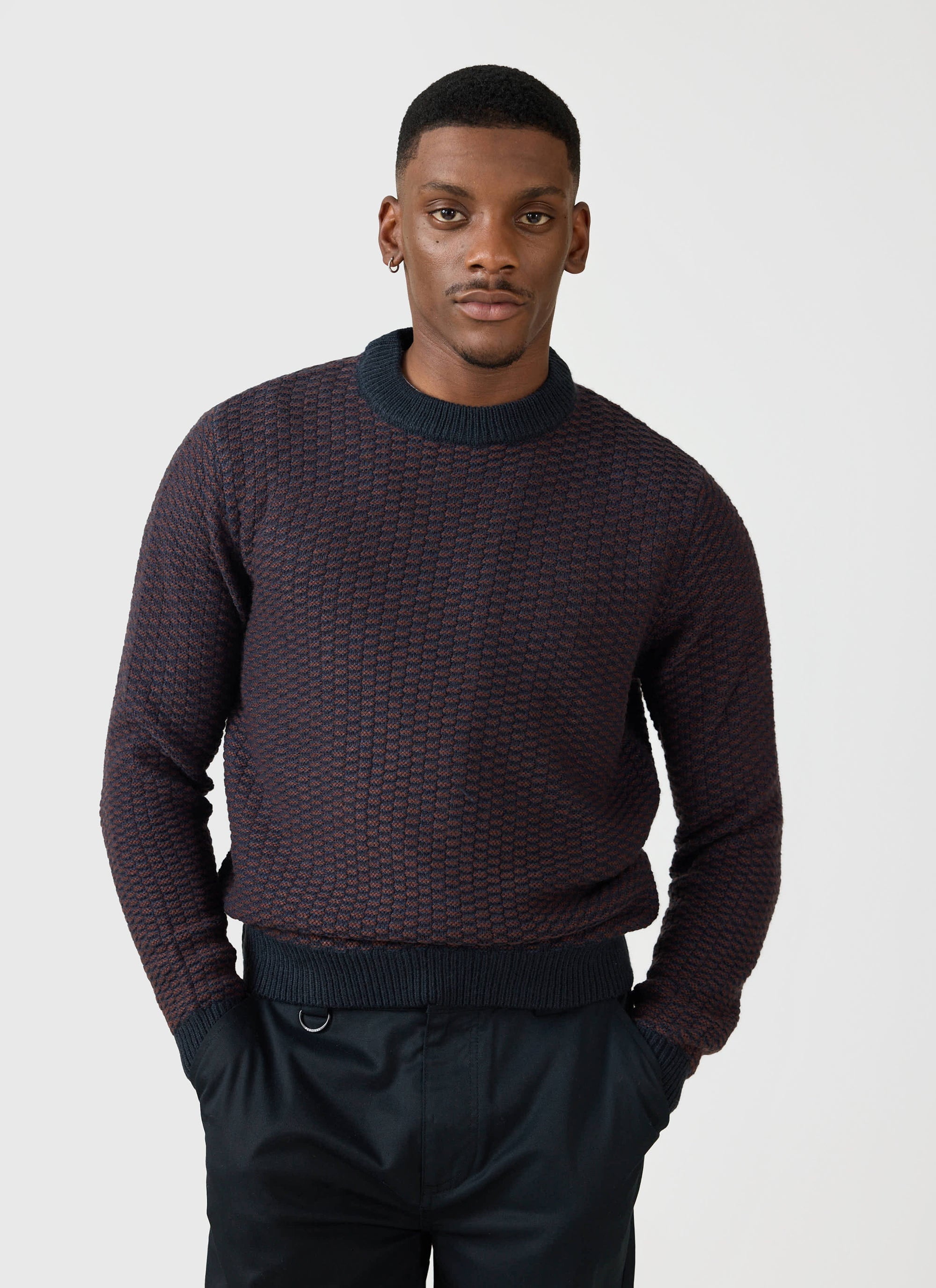 A man models the Percival Charlestown Knitted Jumper in a navy and burgundy textured knit.