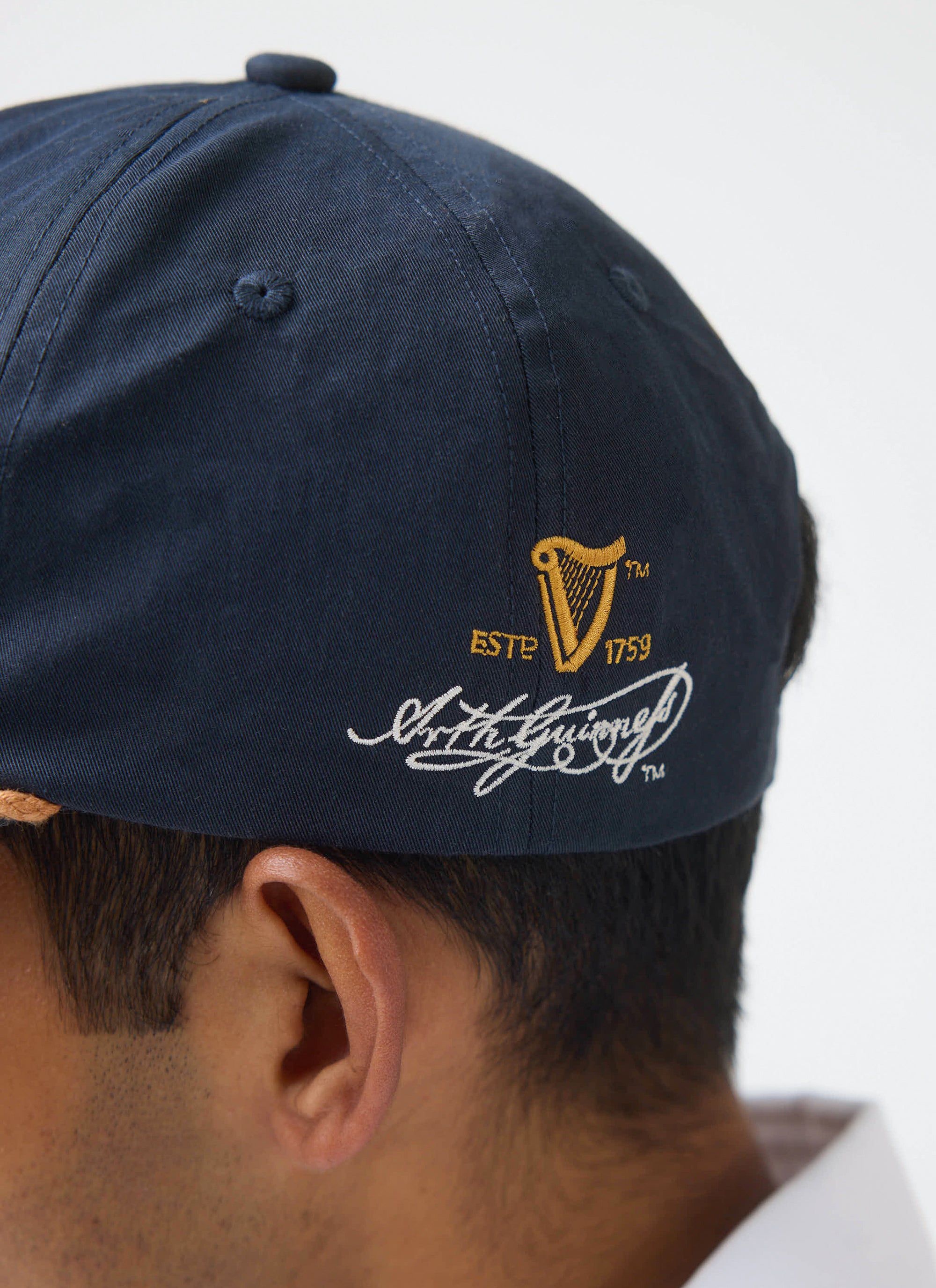 A close-up of the Arthur Guinness signature embroidery on the side of the navy Guinness x Percival cap.