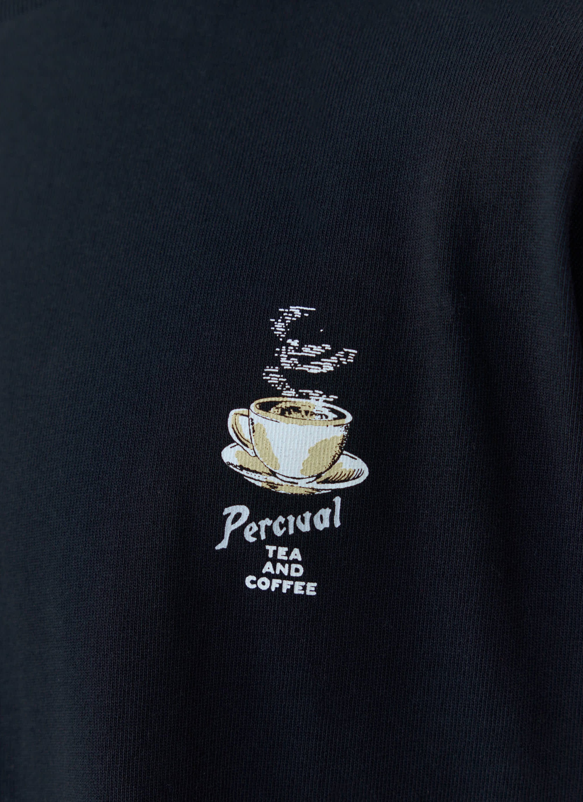 Close-up of the 'Tea and Coffee' graphic embroidered on the chest of the black organic cotton oversized tee from Percival.