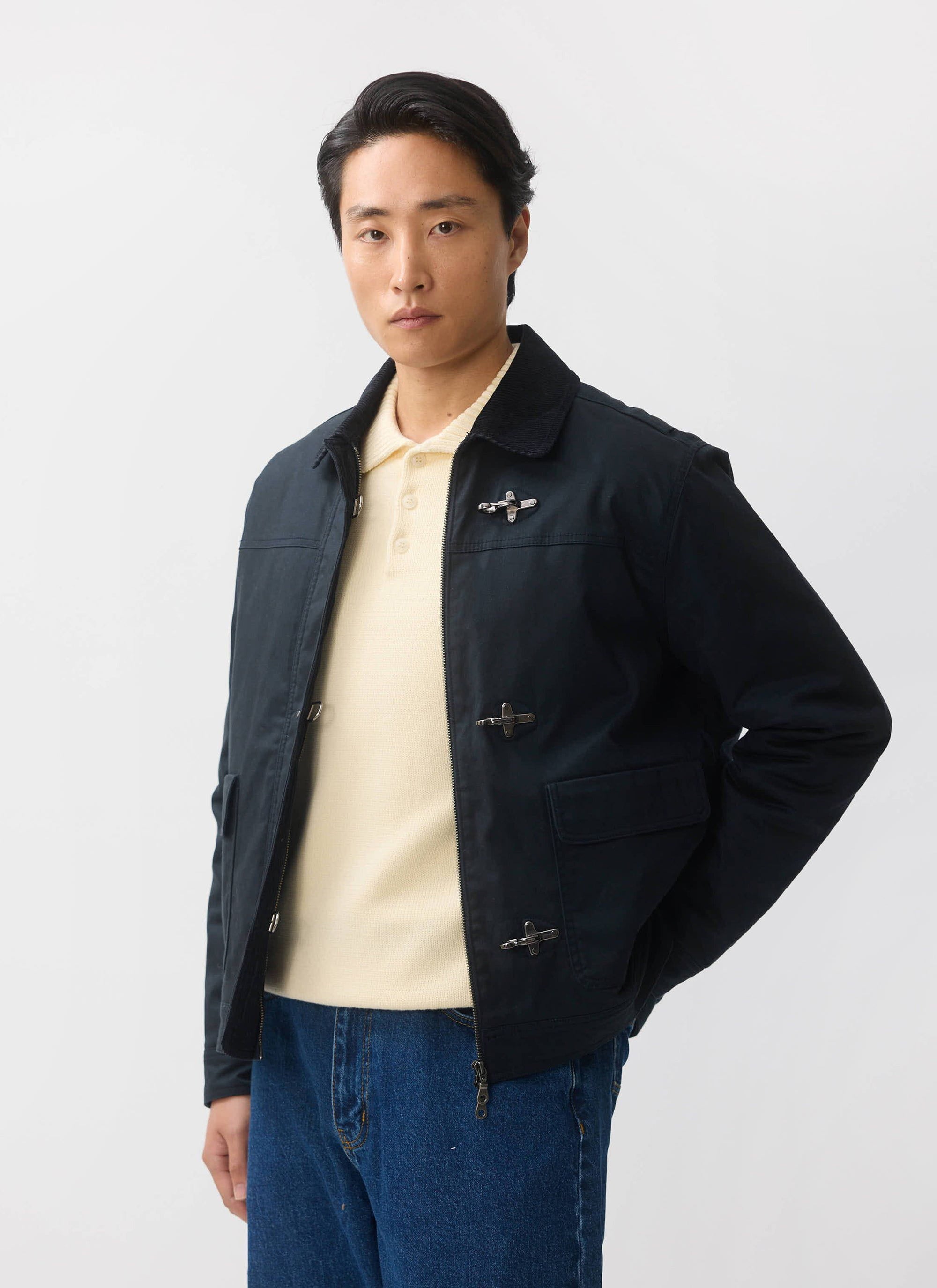 A man models the Percival Fontane Wax Jacket in navy, which features fireman clasps and a corduroy collar.