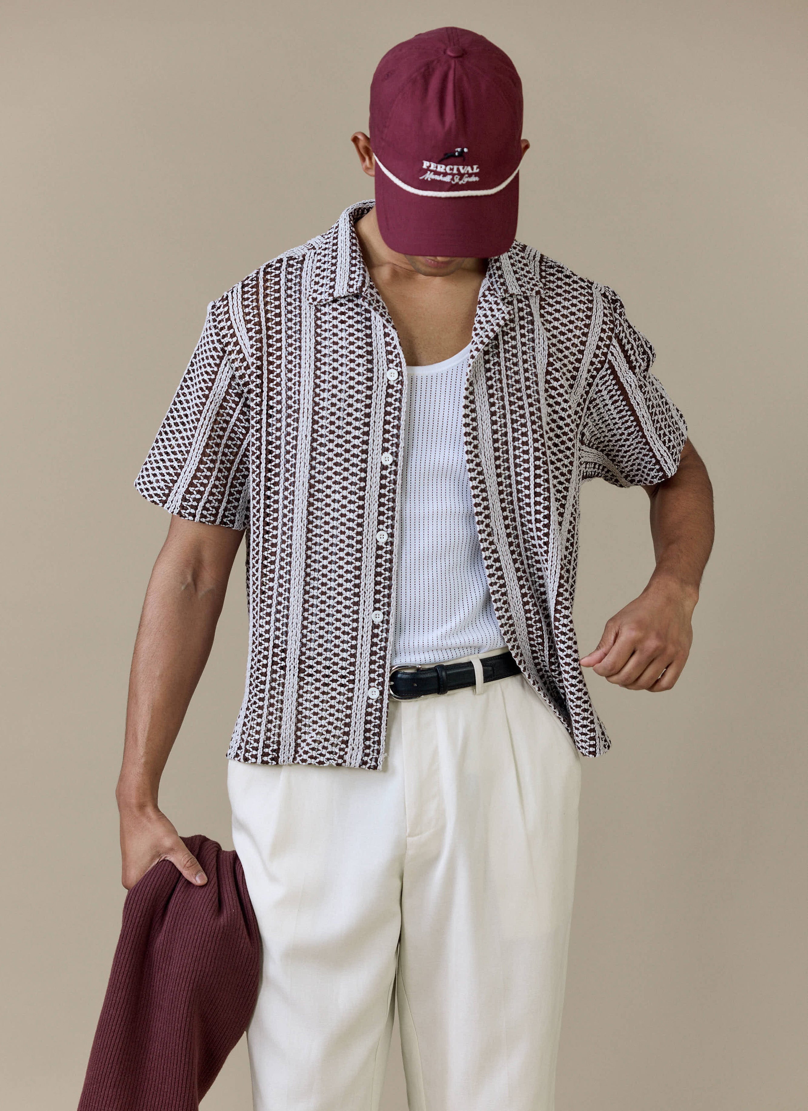 A model wearing the Percival Hugh Crochet Boxy Shirt in brown, featuring a striped crochet knit and revere collar.