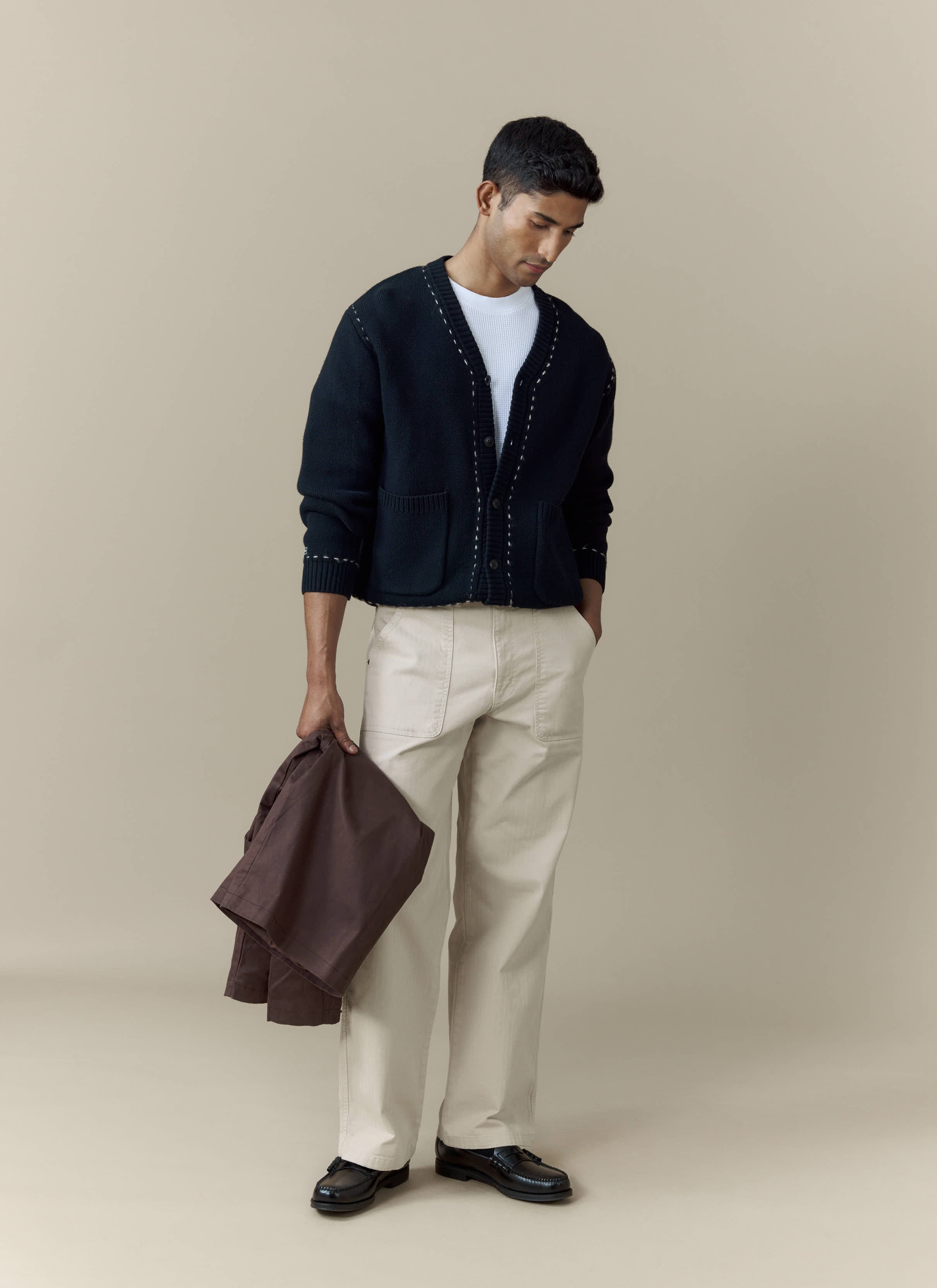 A man models the Percival Module Boxy Cardigan in black, styled with a white tee and light-coloured trousers.