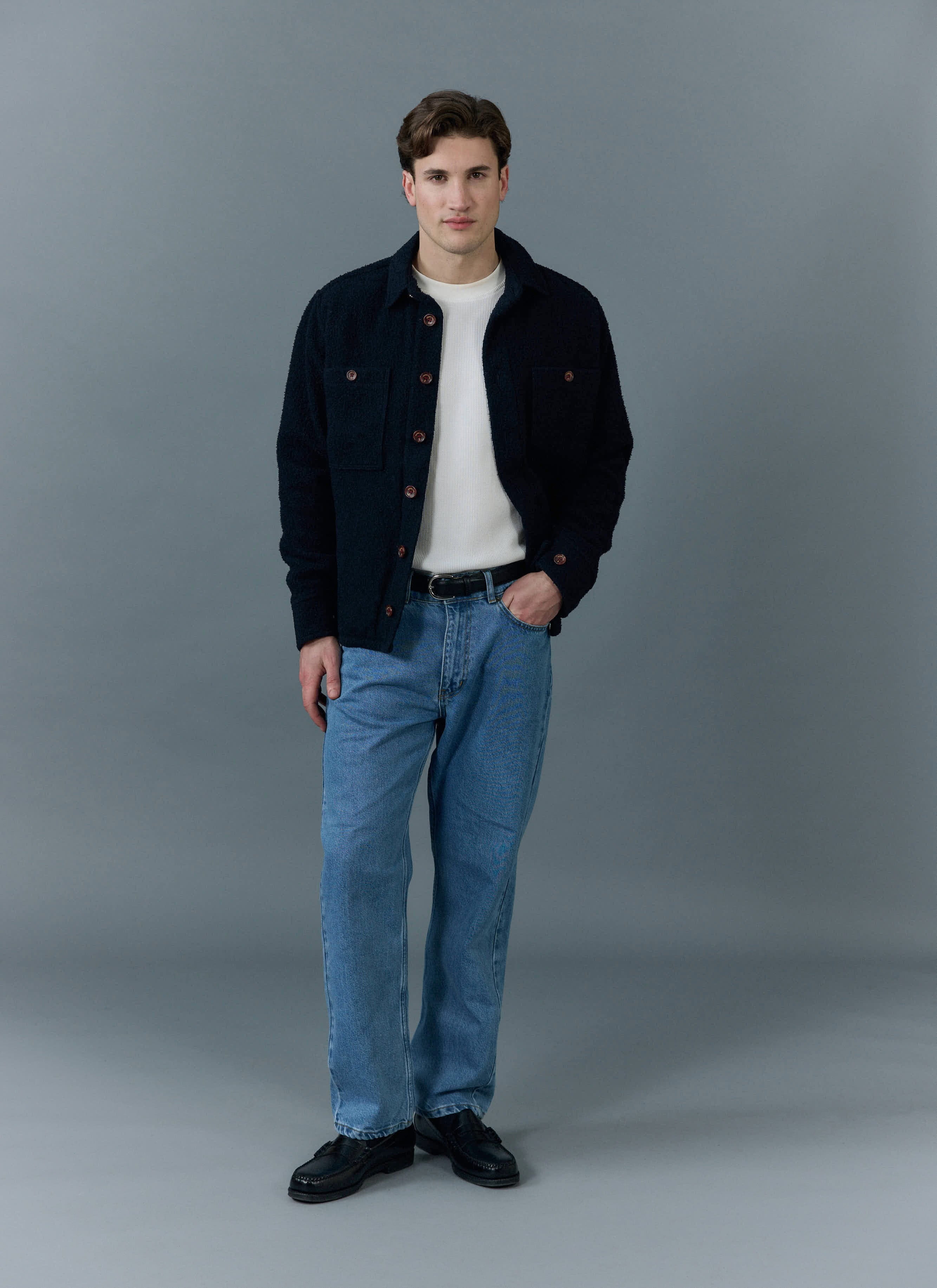 A model wears the Percival Blanket Overshirt in navy Casentino wool, styled with a white top and blue jeans.