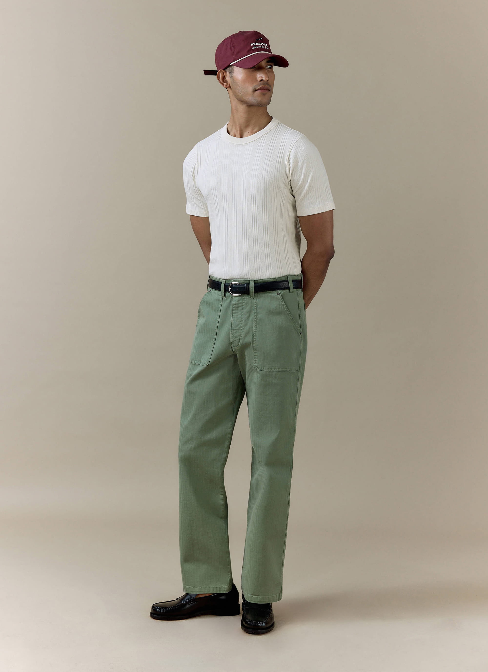 Cream Percival Leon Ribbed T Shirt in organic cotton, styled on a model with green trousers and a maroon baseball cap.