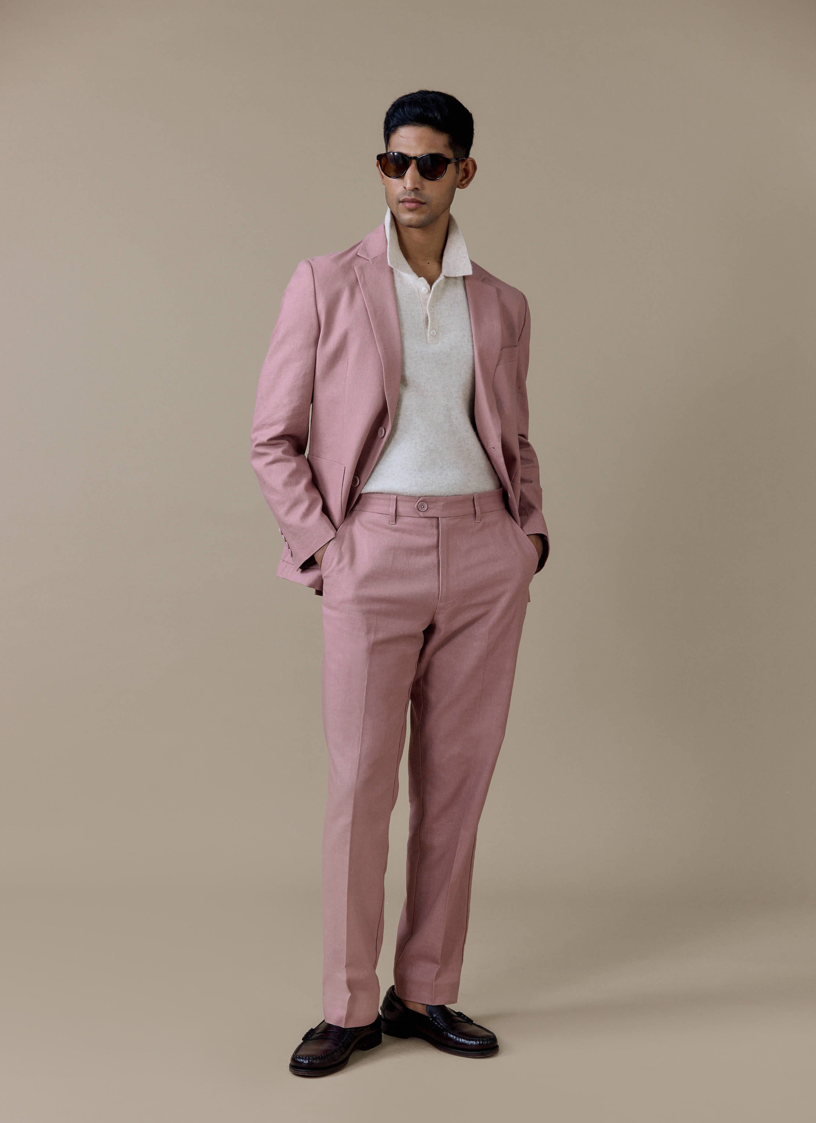 Percival tailored linen blazer in dusty pink styled with matching suit trousers and a cream knitted polo shirt.